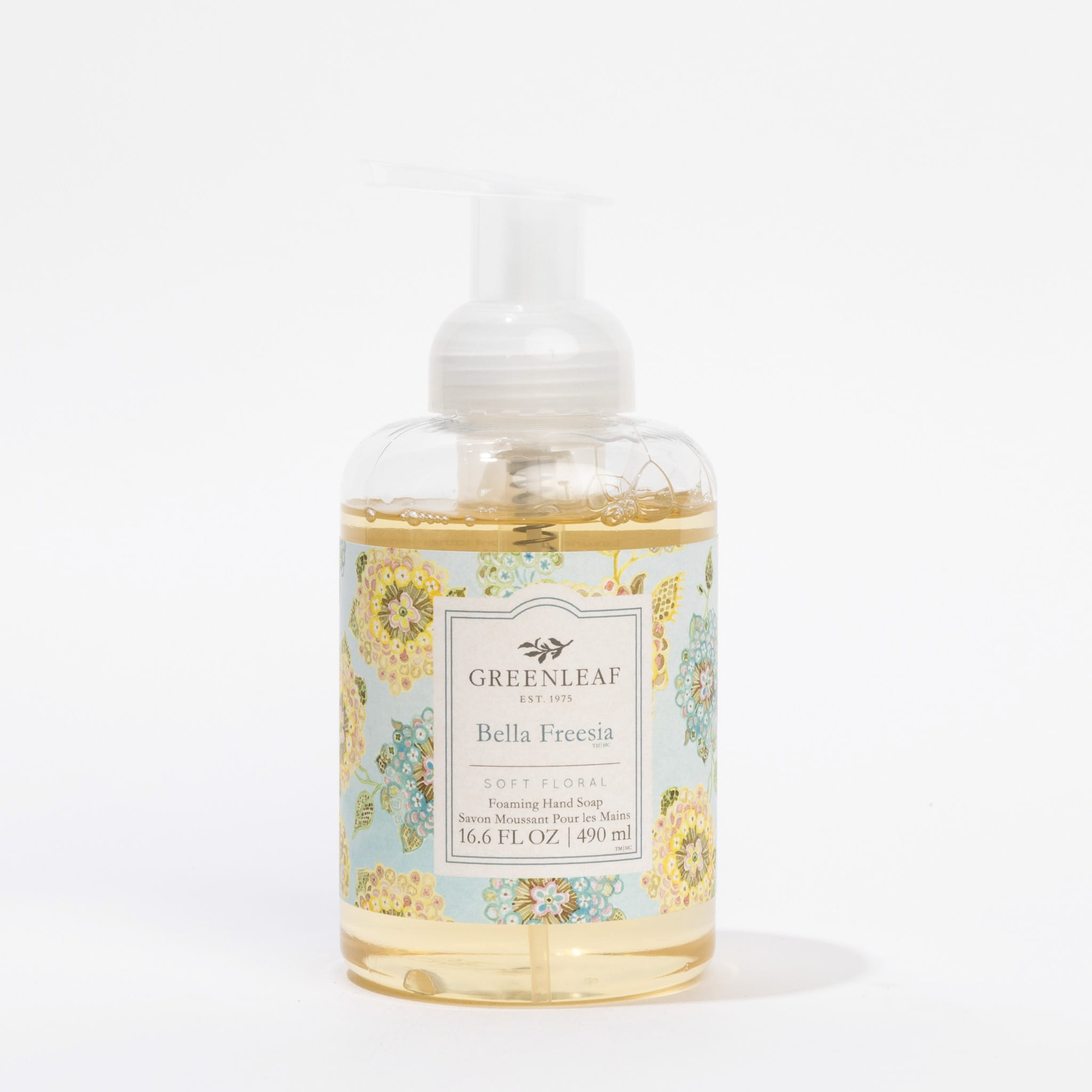 A clear pump bottle of Greenleaf Gifts Bella Freesia Foaming Hand Soap, with a floral label in blue, yellow, and green. The 16.6 FL OZ (490 ml) soap gently cleanses hands and is enriched with coconut oil for added moisture.