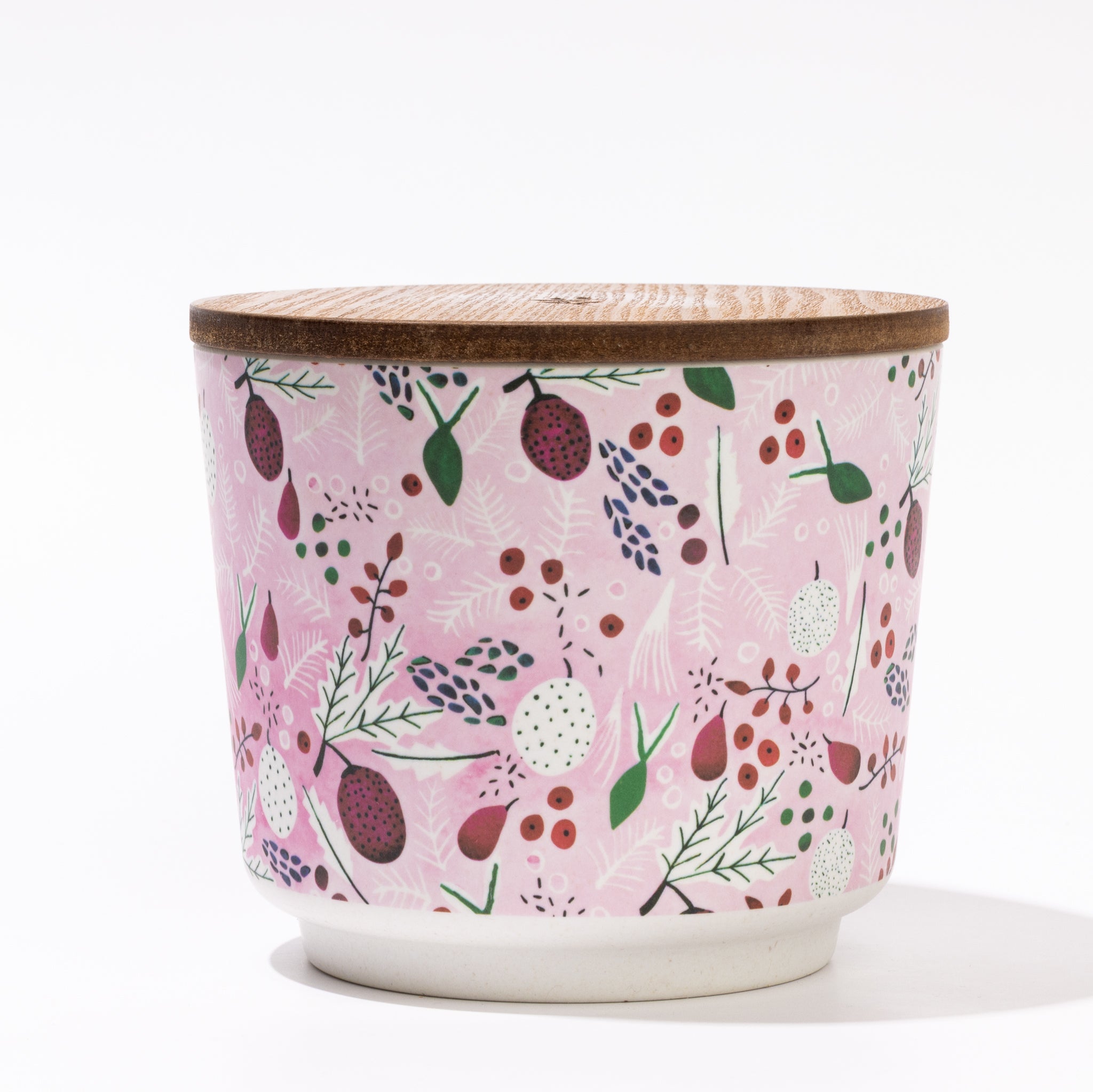 The Brambleberry Patterned 3 Wick Candle by Greenleaf Gifts features a round ceramic container with a wooden lid, adorned with playful leaves, berries, and abstract shapes on a pink background—adding charm to any space.