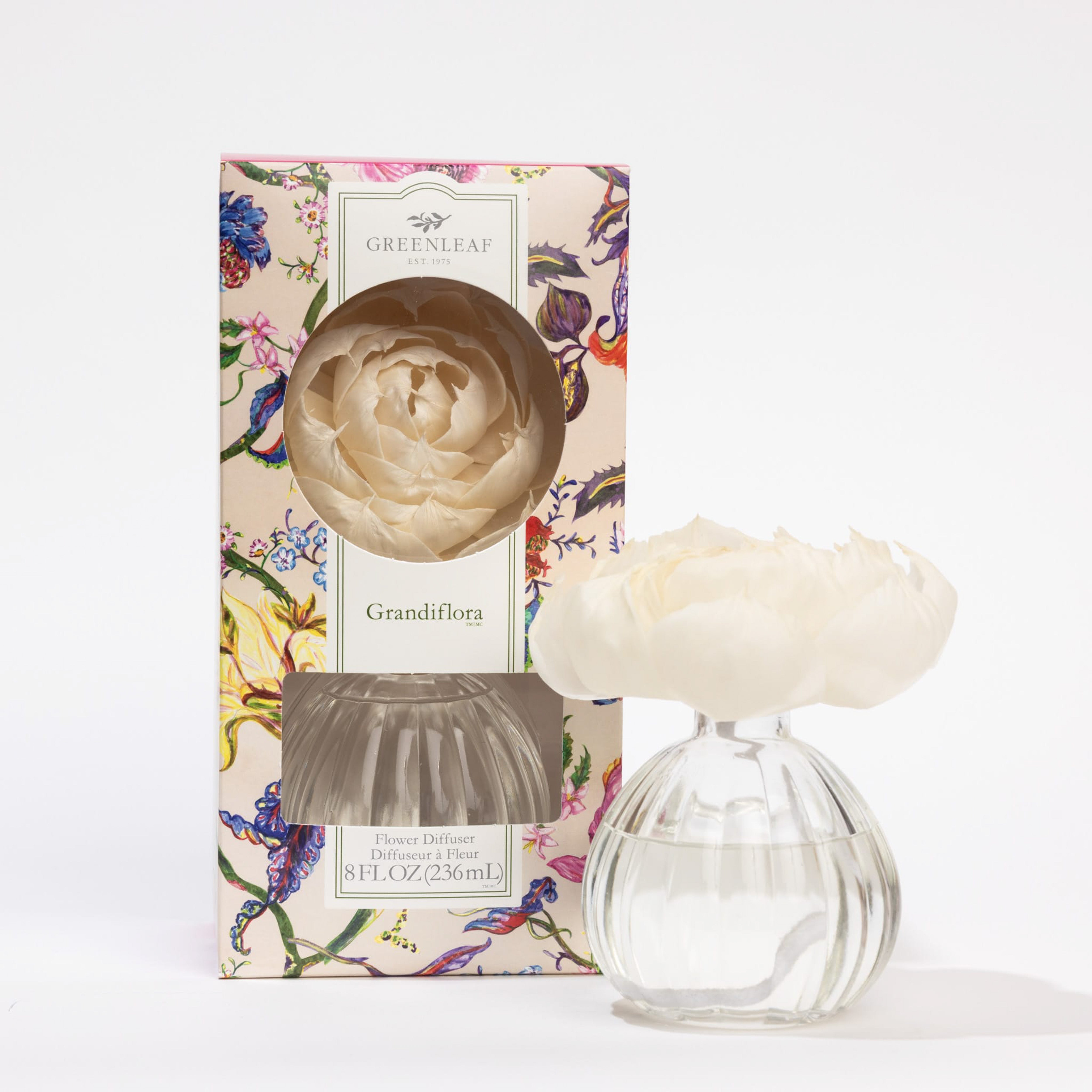 The Greenleaf Gifts Grandiflora Flower Diffuser set features a clear round vase with water, topped by a white sola peony flower, and comes in a floral-patterned box with fragrance oil, displayed against a white background.