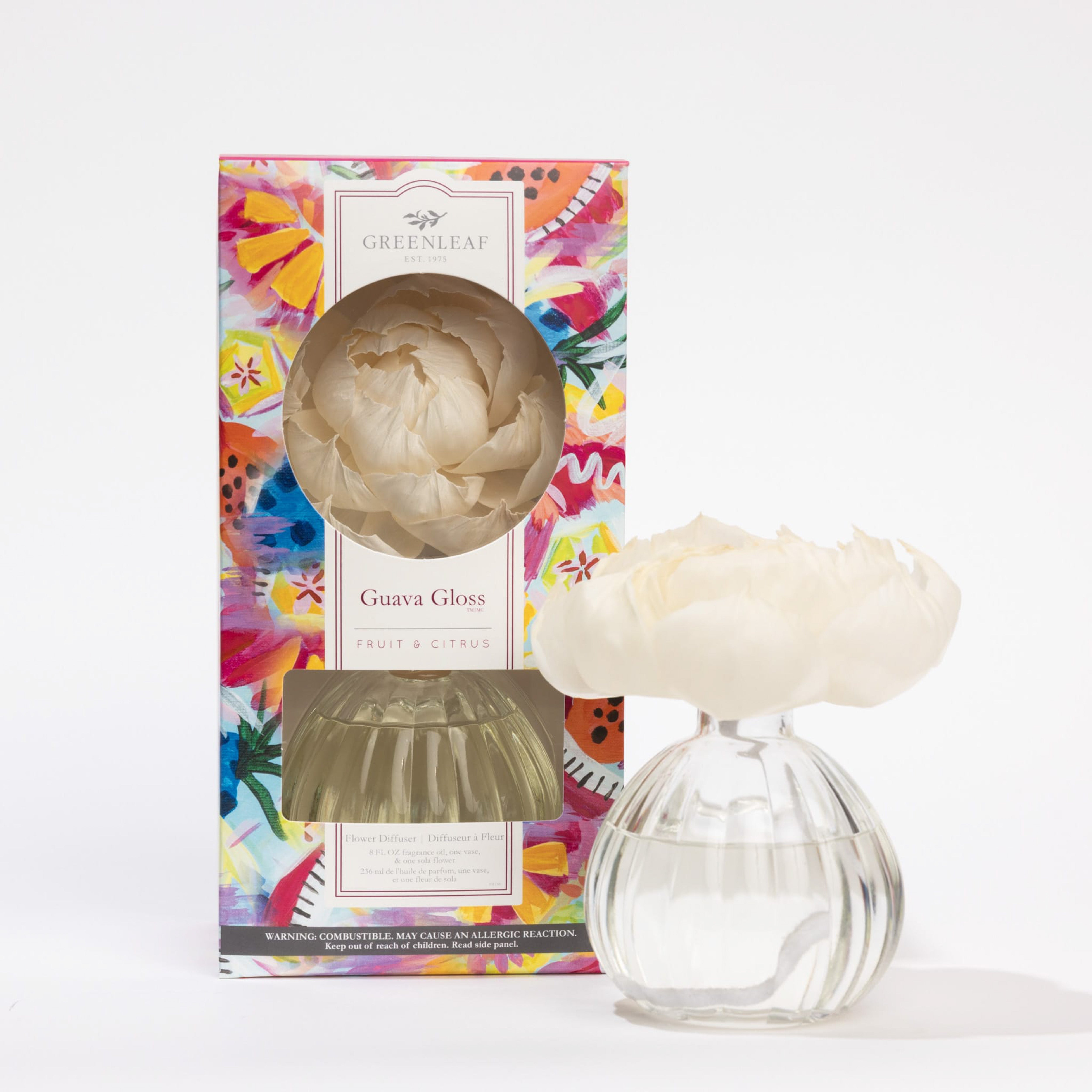 A Greenleaf Gifts Guava Gloss Flower Diffuser with a white sola paper flower sits next to its vibrant, abstract-patterned box featuring the Greenleaf Gifts brand and premium fragrance oil.