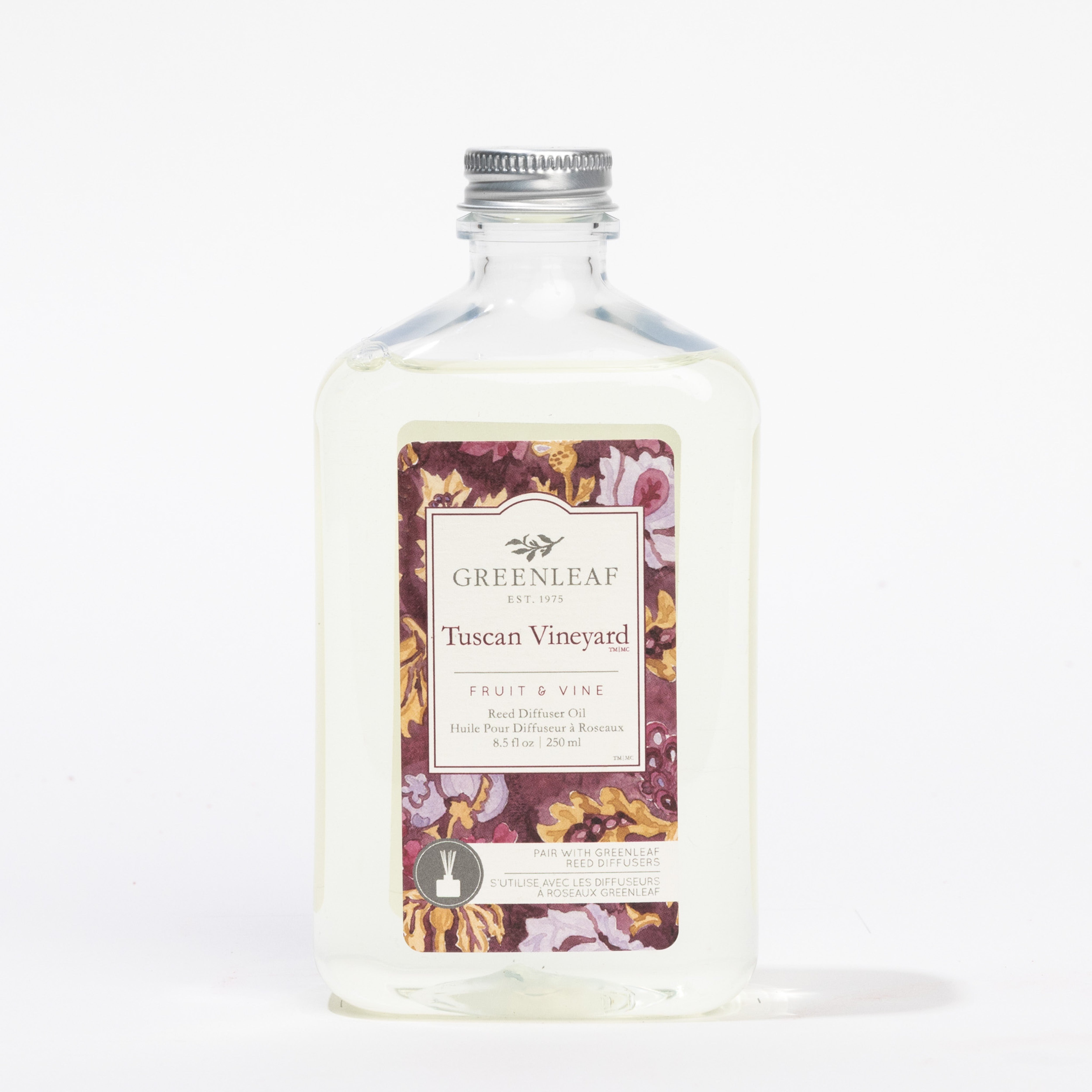 A clear glass bottle with a silver cap labeled Greenleaf Gifts Tuscan Vineyard Diffuser Oil Refill, 250 ml. The floral label describes it as a replacement oil capturing the lush essence of a Tuscan vineyard for your reed diffuser.