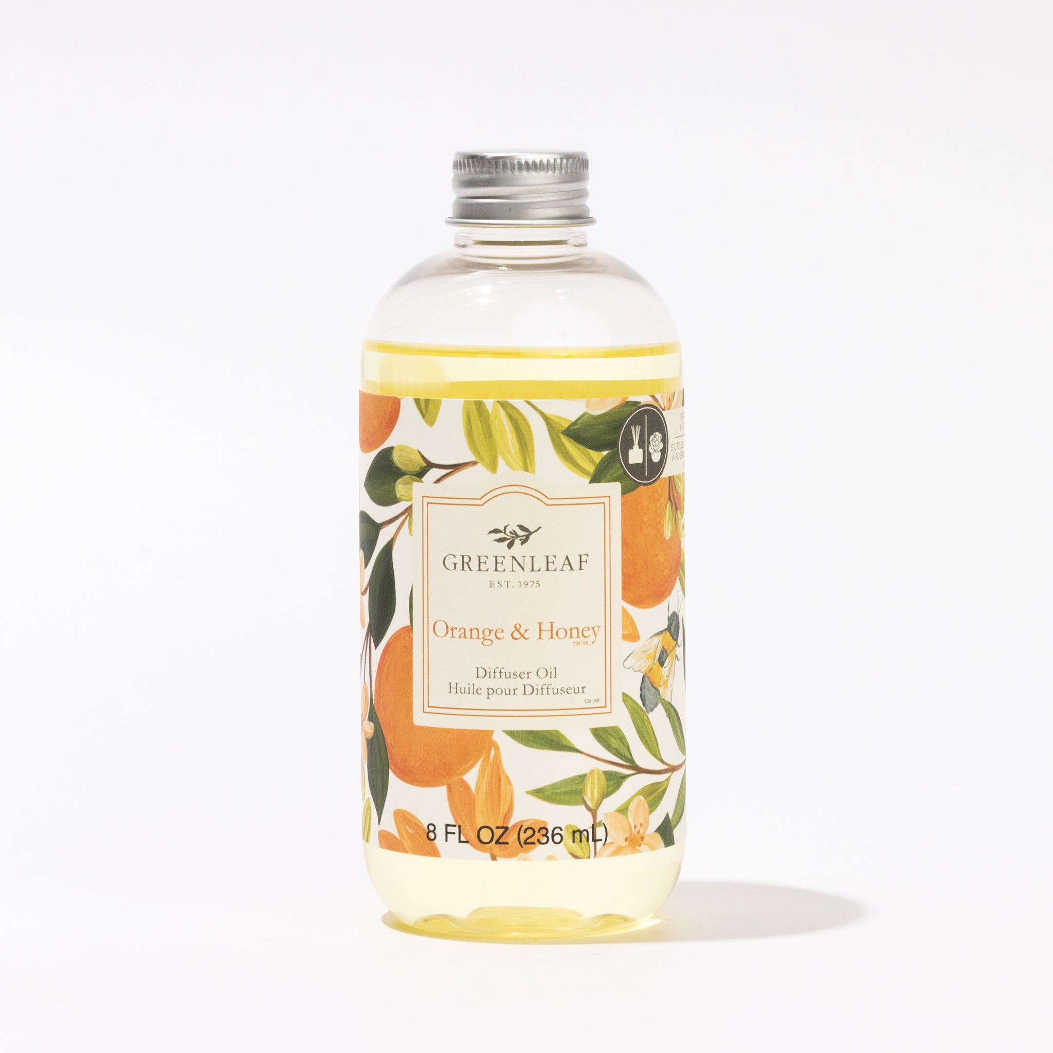 A clear bottle of Greenleaf Gifts Orange & Honey Diffuser Oil with a silver cap features orange and floral label art. The 8 fl oz (236 ml) oil is ideal for use in your Greenleaf Reed Diffuser.