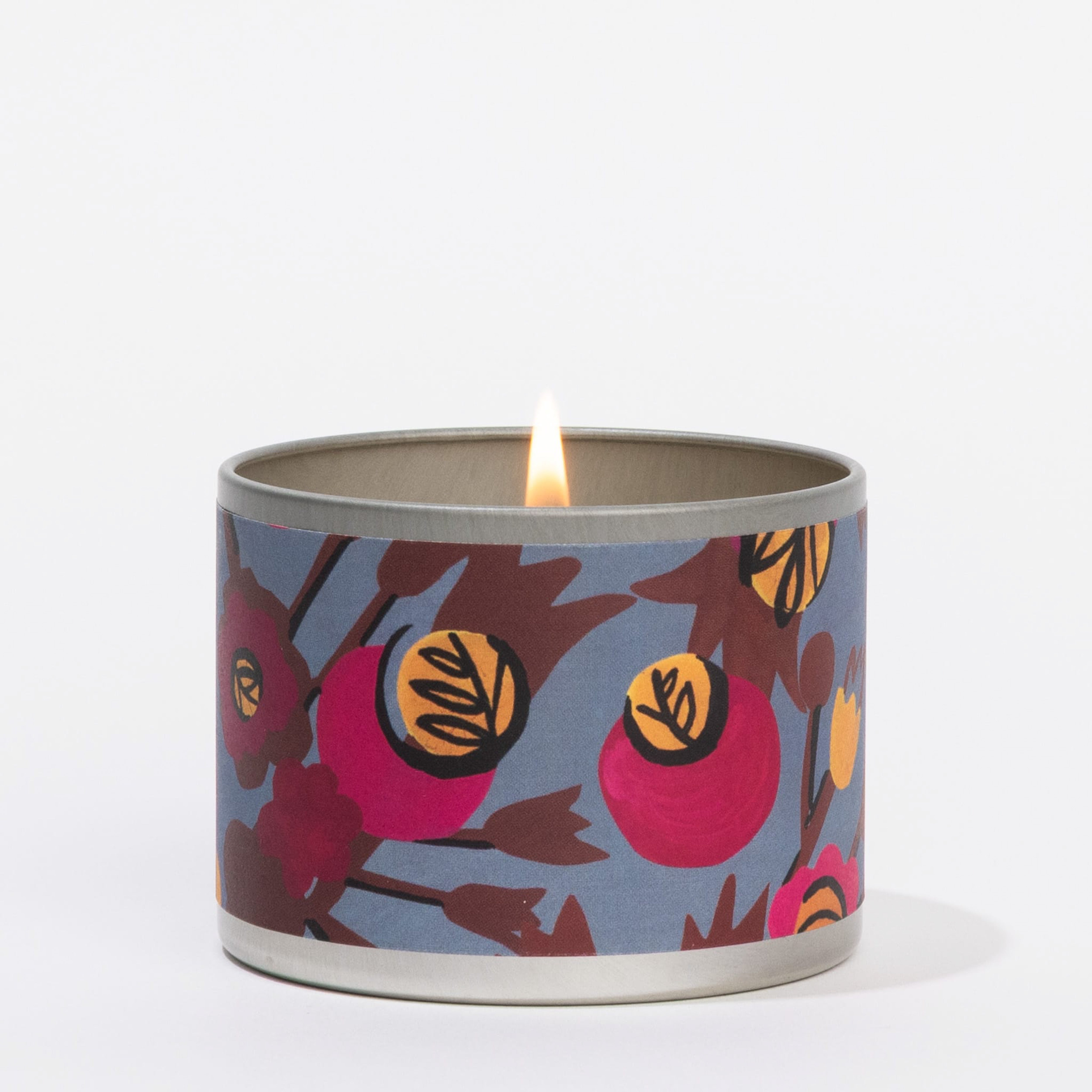 The Greenleaf Gifts Rhubarb & Oak Tin Candle features a floral-patterned round tin with a blue background, emitting a rhubarb and oak scent. It is showcased against a plain white backdrop.