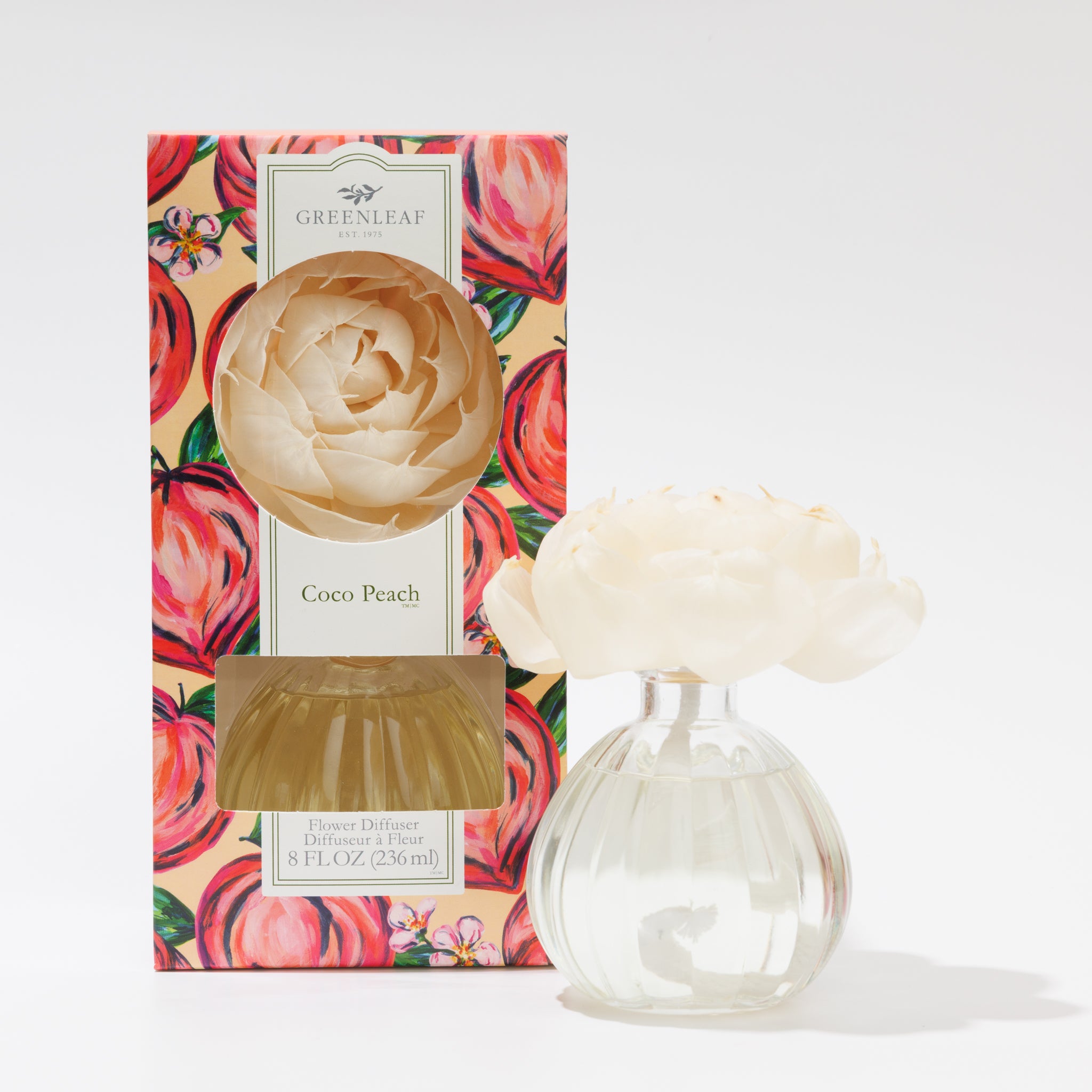 The Greenleaf Gifts Coco Peach Flower Diffuser features a cream sola flower in a round glass bottle beside its peach-patterned box, filled with refreshing Greenleaf fragrance oil.