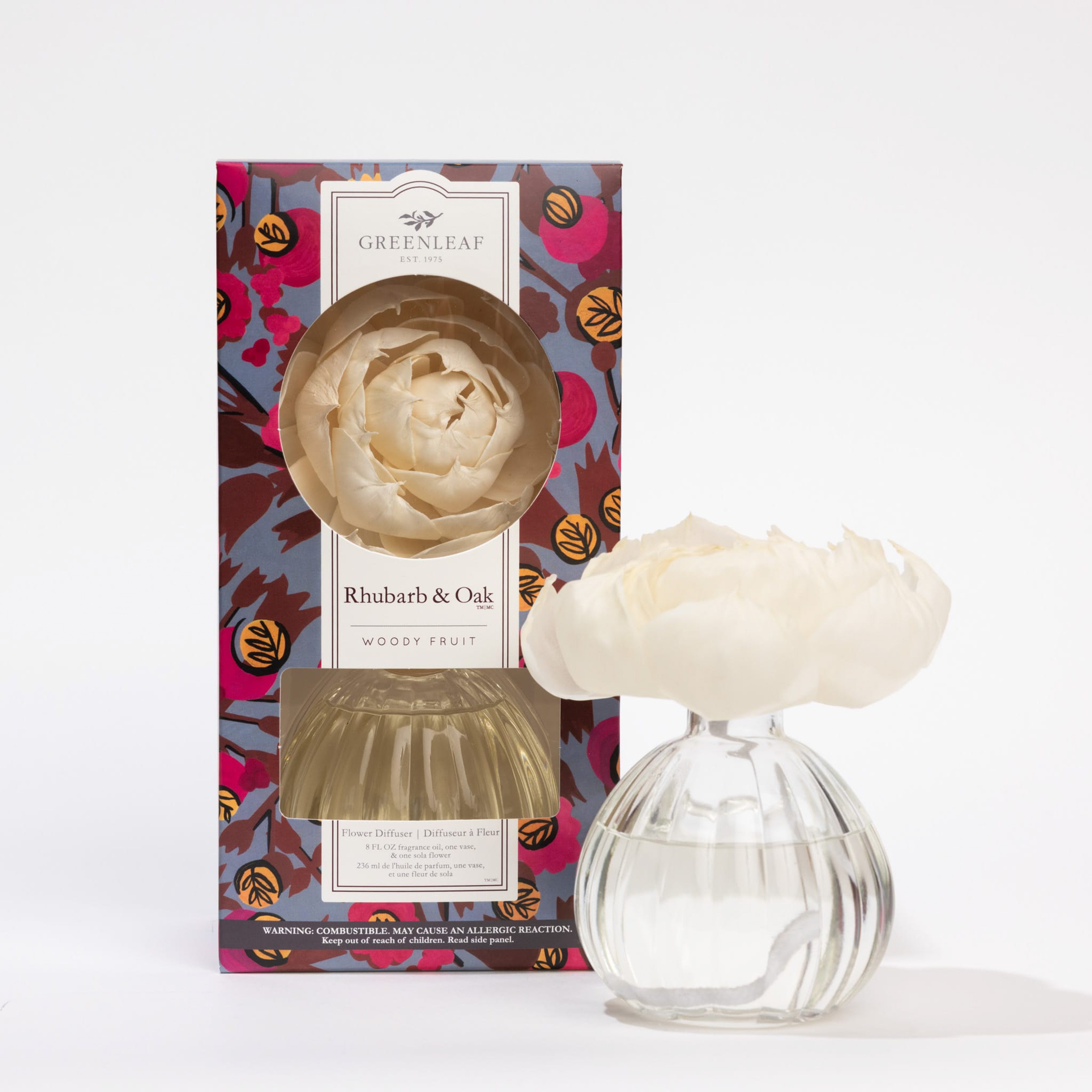 The Greenleaf Gifts Rhubarb & Oak Flower Diffuser features an 8 oz clear glass vase with a white flower-shaped diffuser in a colorful box, offering up to 60 days of fragrance.