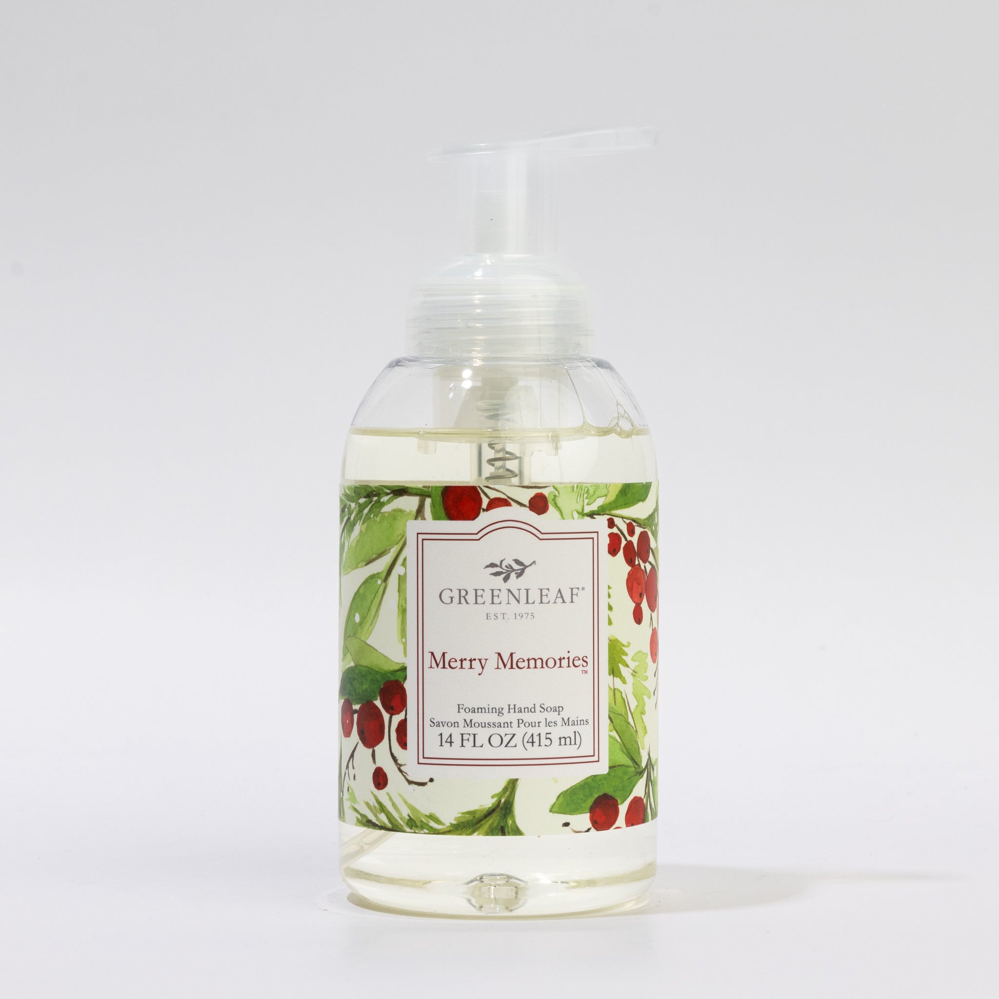 A 14 oz clear plastic pump bottle of Merry Memories Foaming Hand Soap by Greenleaf Gifts, featuring a festive label with green leaves and red berries.