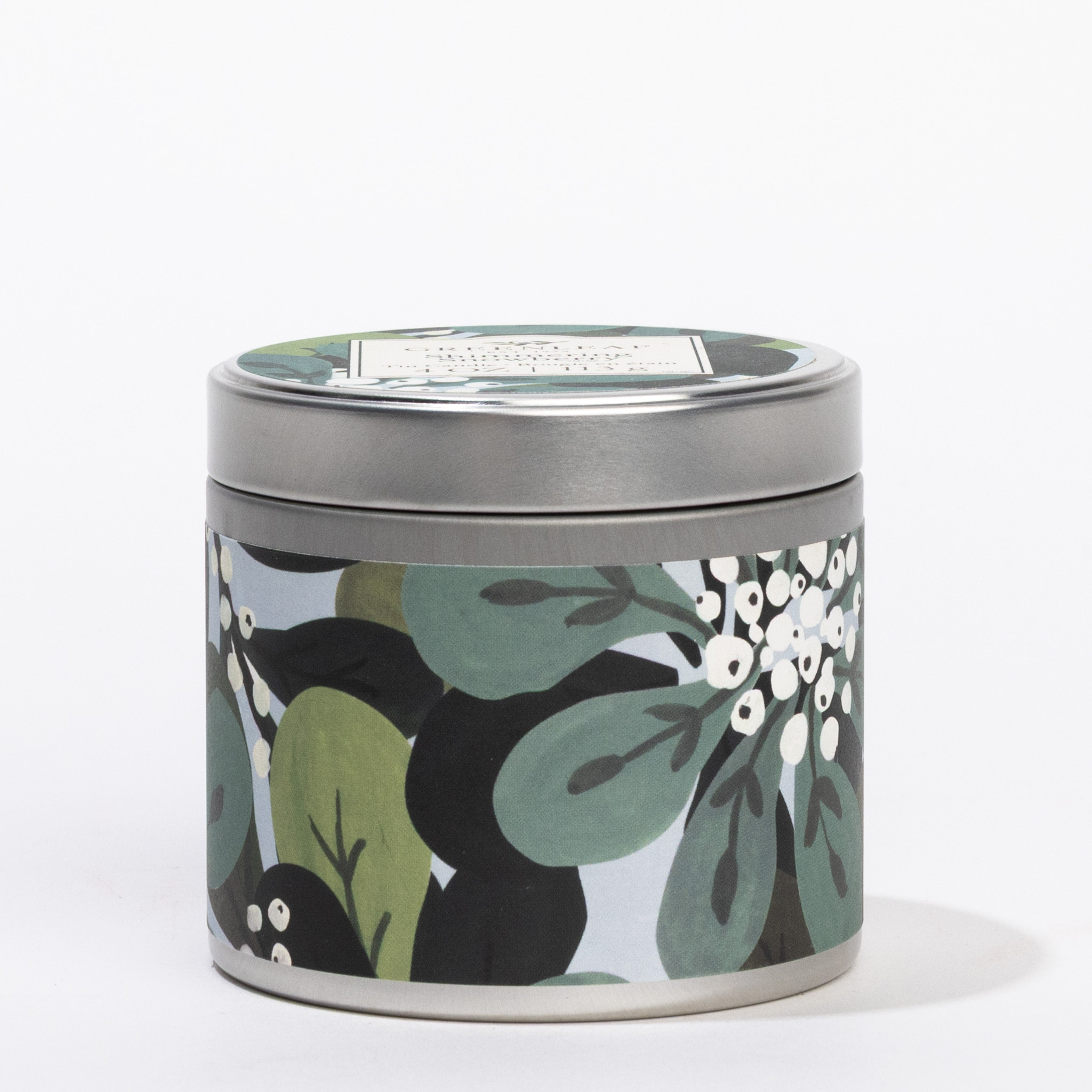 The Greenleaf Gifts Shimmering Snowberry Tin Candle features a silver lid and a light design with green leaves and white flowers. Ideal for travel, it fills any space with its refreshing Shimmering Snowberry scent.