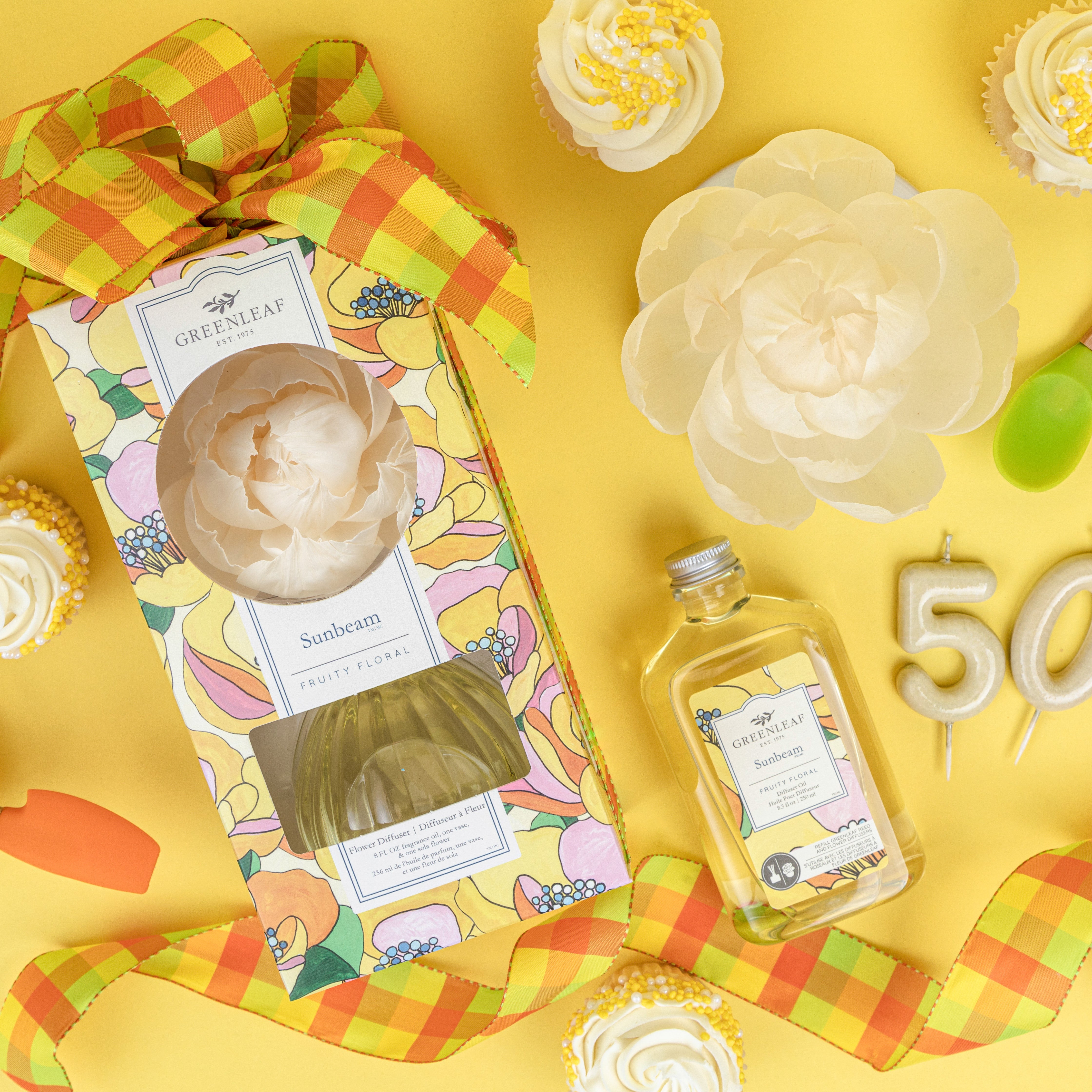 A floral-themed gift set featuring a Greenleaf Gifts Reed Diffuser with Sunbeam fragrance and a Sunbeam Diffuser Refill Oil, surrounded by yellow and white cupcakes, a white flower, green spoons, and birthday candles forming 50 on a yellow background.