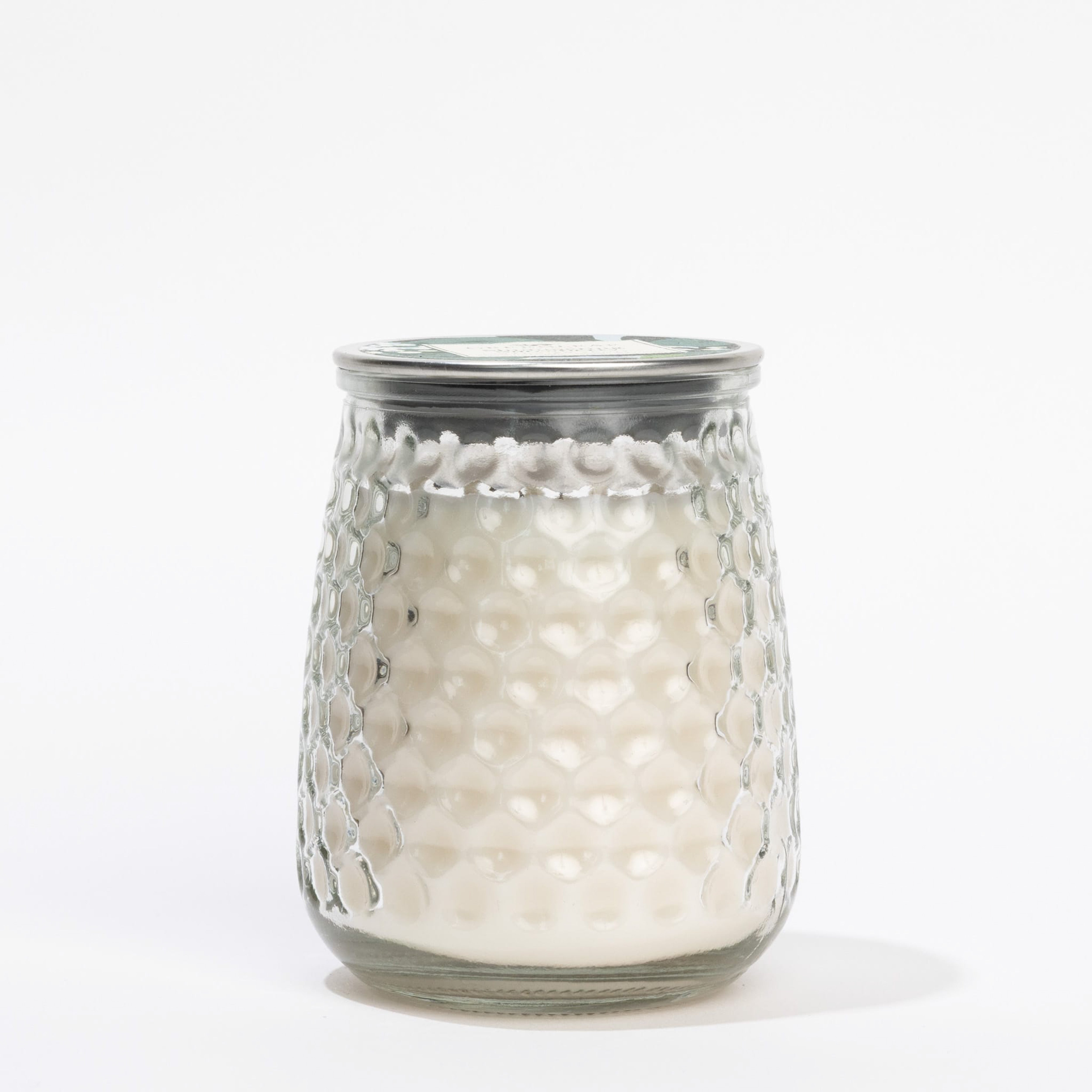 A textured glass jar with white wax and a metal lid is likely the Greenleaf Gifts Shimmering Snowberry Signature Candle, shown against a plain white background.