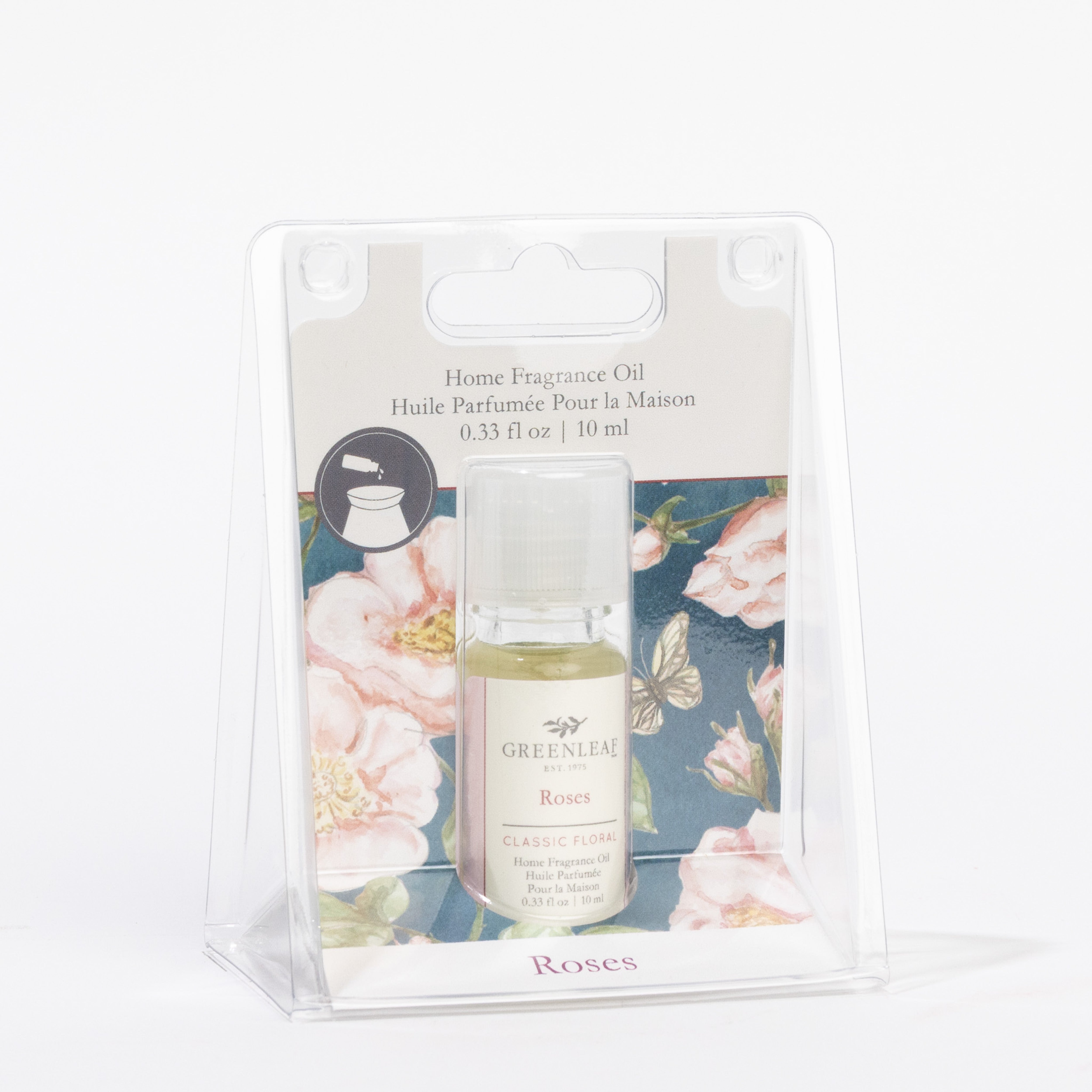A small bottle of Greenleaf Gifts Roses Home Fragrance Oil offers an elegant, flameless rose scent, packaged in a clear plastic case with a floral background and product details above the bottle.