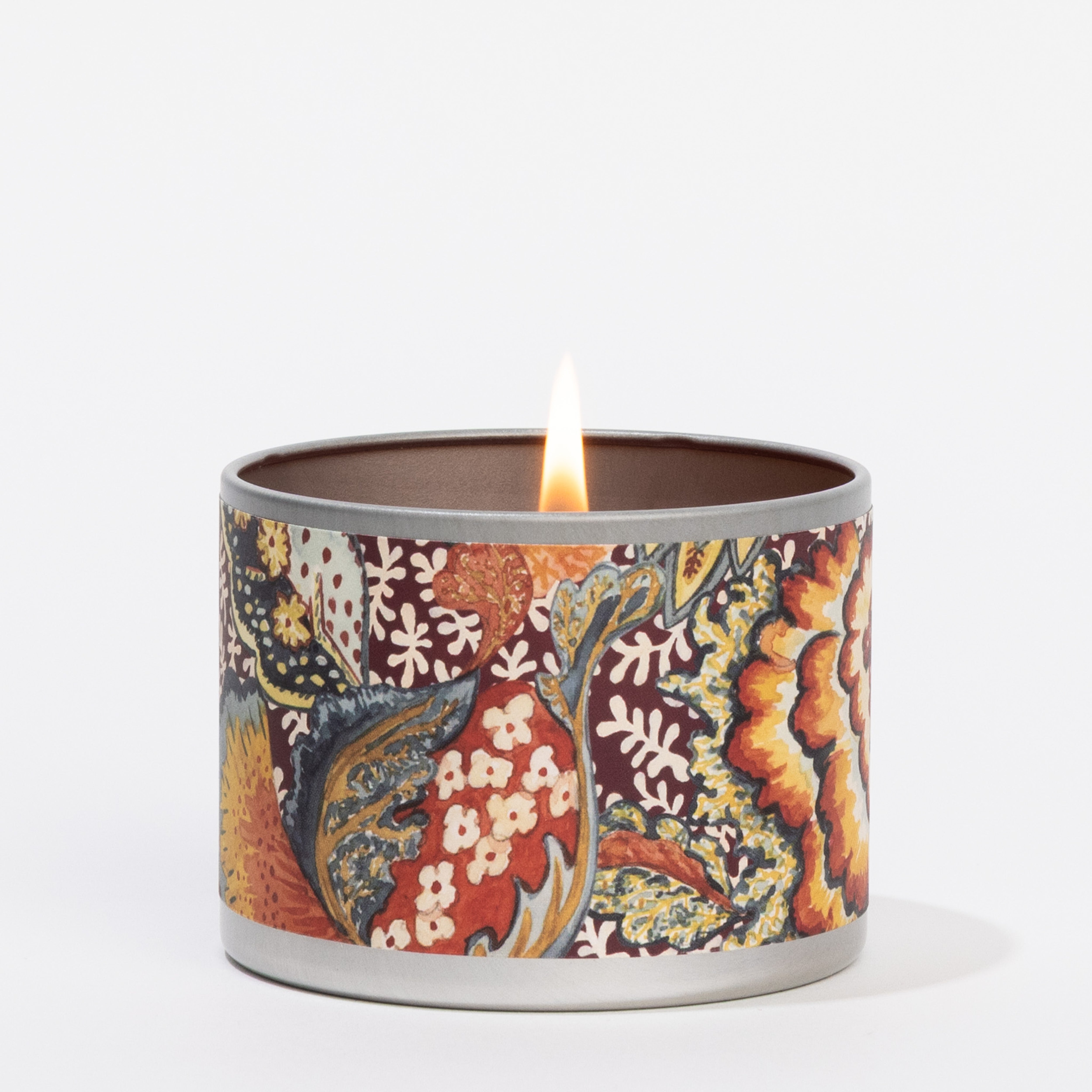 The Hope Tin Candle by Greenleaf Gifts, in a round metal container with an intricate, colorful floral and leaf design, fills your home with cozy fragrance against a white background.