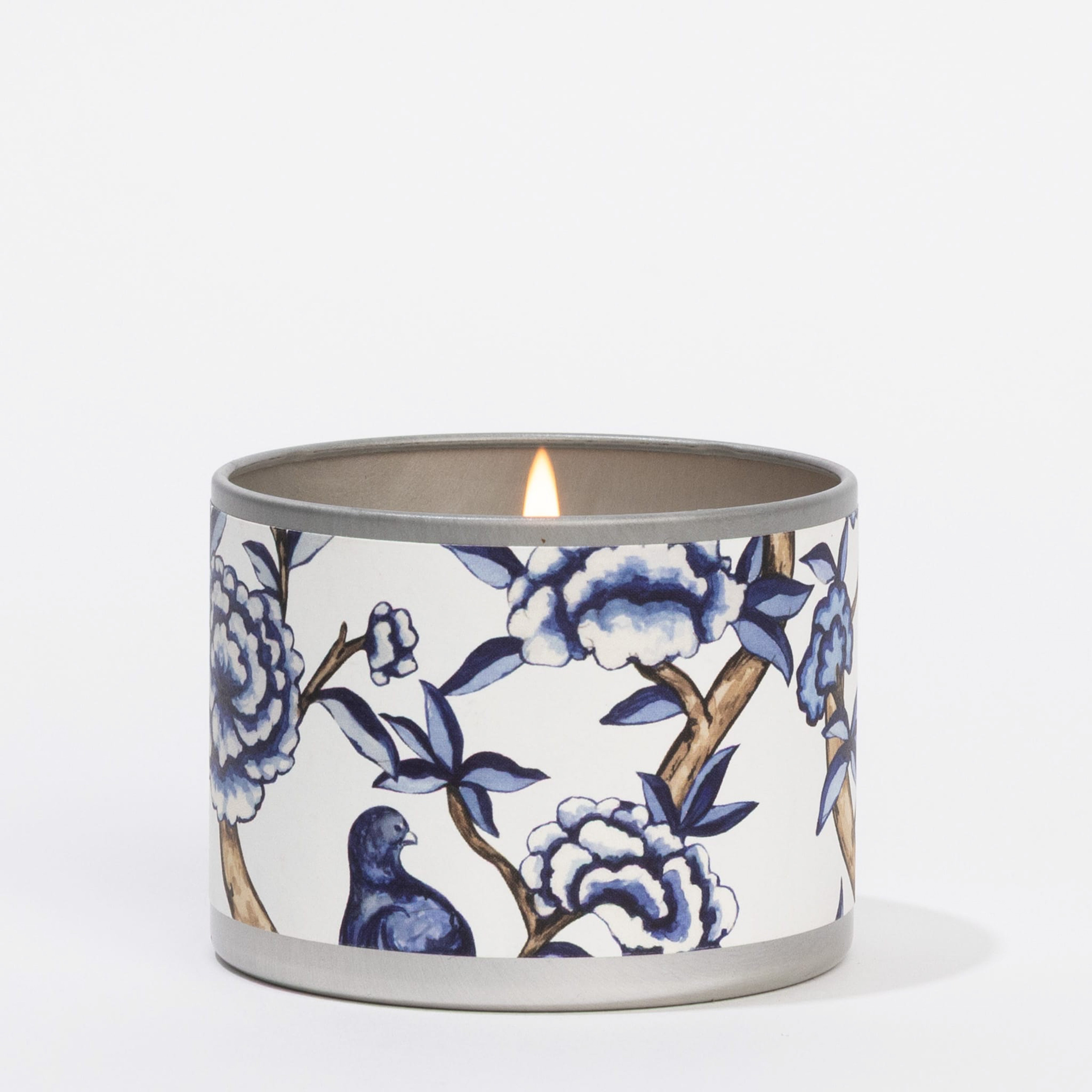 The Classic Linen Tin Candle by Greenleaf Gifts comes in a round holder with blue and white floral and bird patterns on a white background.