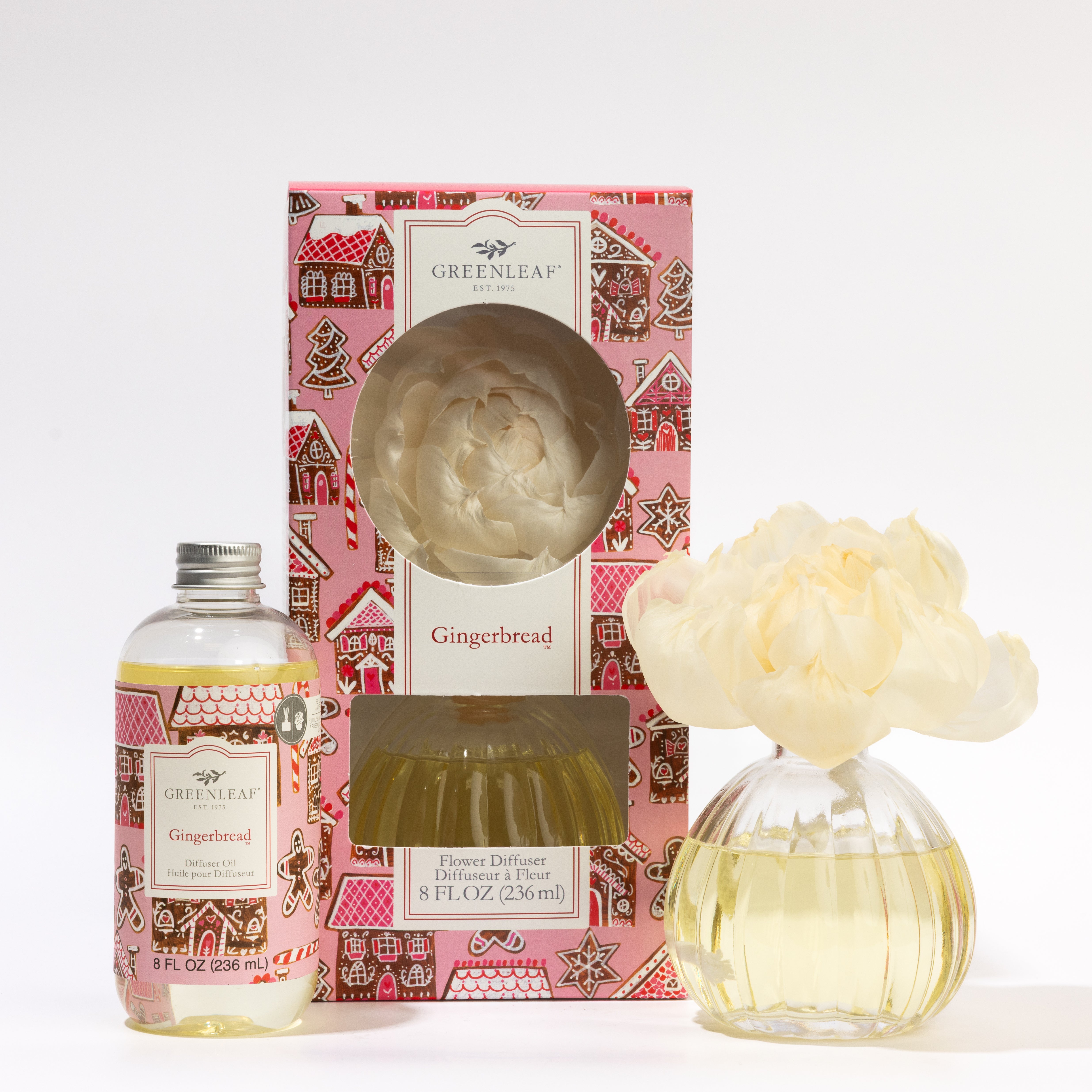 The Fast Bundle Gingerbread Flower Diffuser & Fragrance Refill Oil set features a diffuser bottle with yellow liquid, a cream faux flower, and decorative packaging with gingerbread house designs.