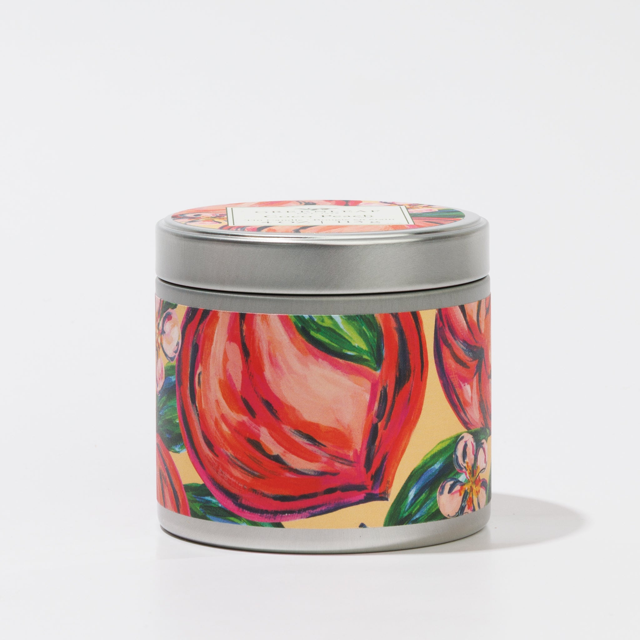 The Coco Peach Tin Candle by Greenleaf Gifts features a round tin with a lid, adorned with hand-painted peaches and green leaves on yellow. Portable and stylish, it's perfect for enjoying the warm Cocoa Peach scent anywhere.