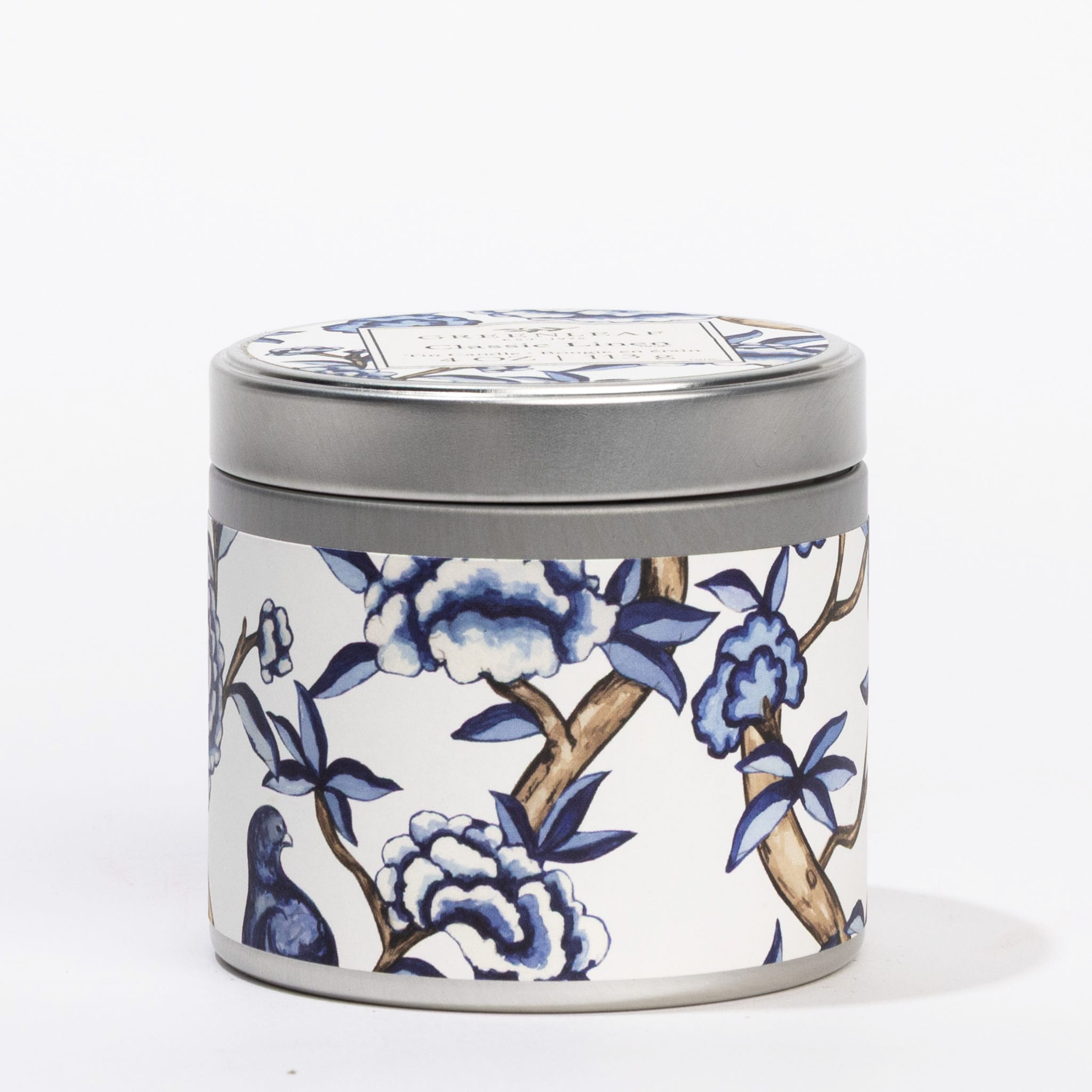 The Classic Linen Tin Candle by Greenleaf Gifts is a round metal tin with a silver lid, featuring a blue and white floral and bird design—perfect as a portable candle to add charm and elegance to any space.