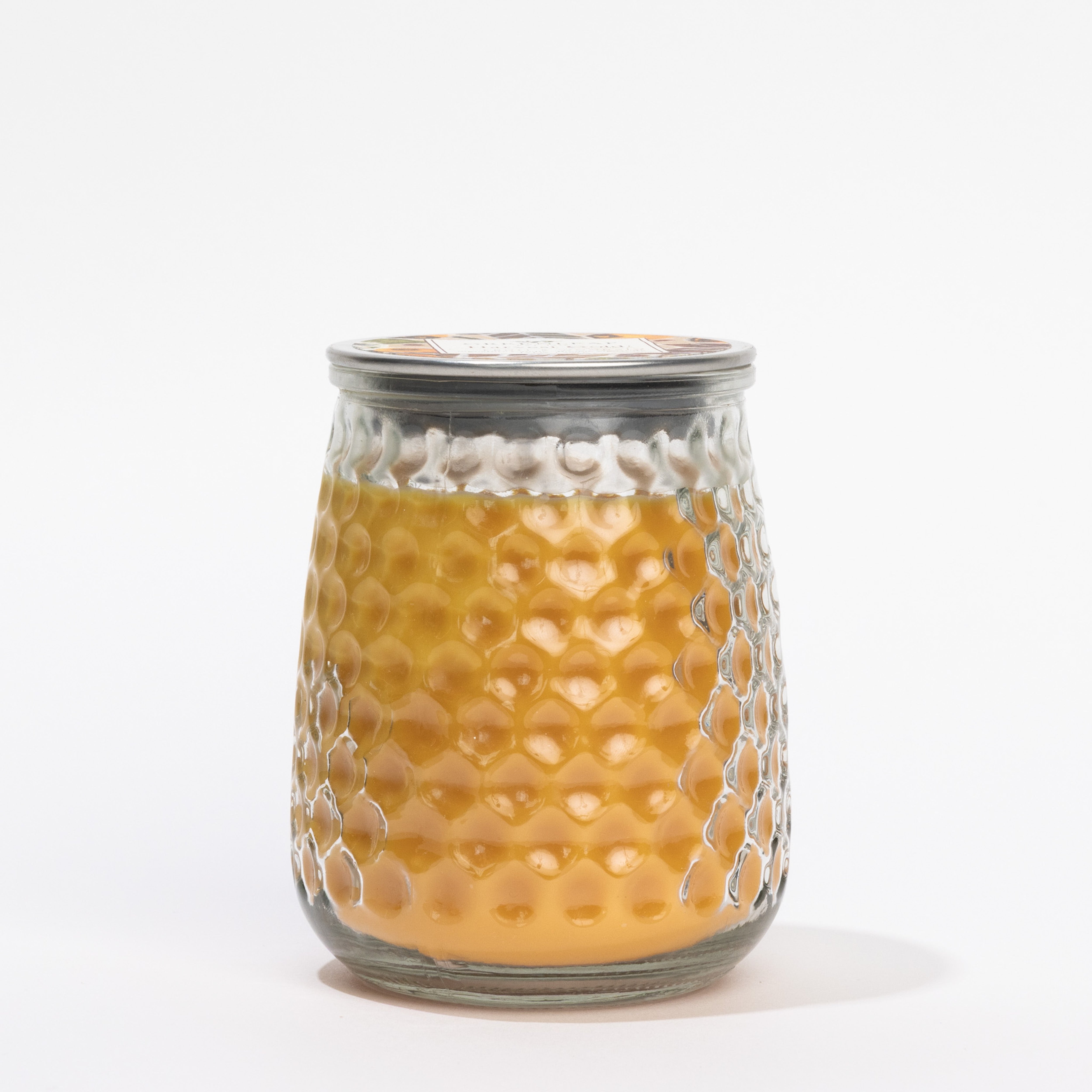 The Harvest Gold Signature Candle by Greenleaf Gifts features a honeycomb-patterned glass jar with a metal lid in rich golden tones, set against a plain white background.