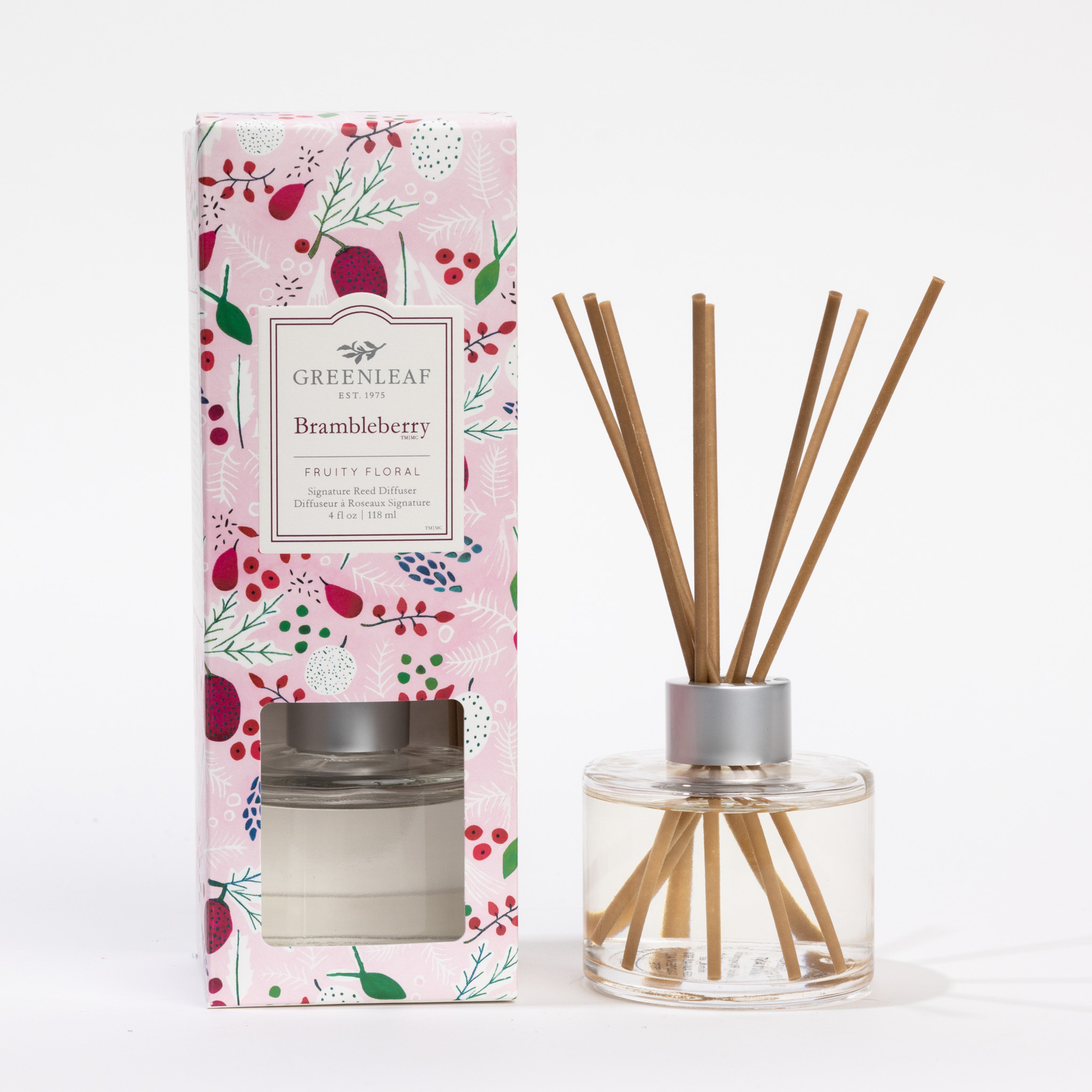 A Greenleaf Gifts Brambleberry Reed Diffuser with brambleberry fragrance is displayed beside its pink floral box, featuring fiber reeds placed in a clear glass bottle.