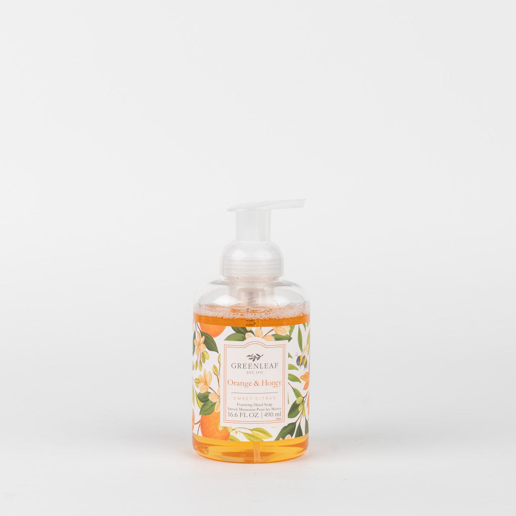 A clear pump bottle of Greenleaf Gifts Orange & Honey Foaming Hand Soap features orange liquid and a floral, orange-themed label against a white background.