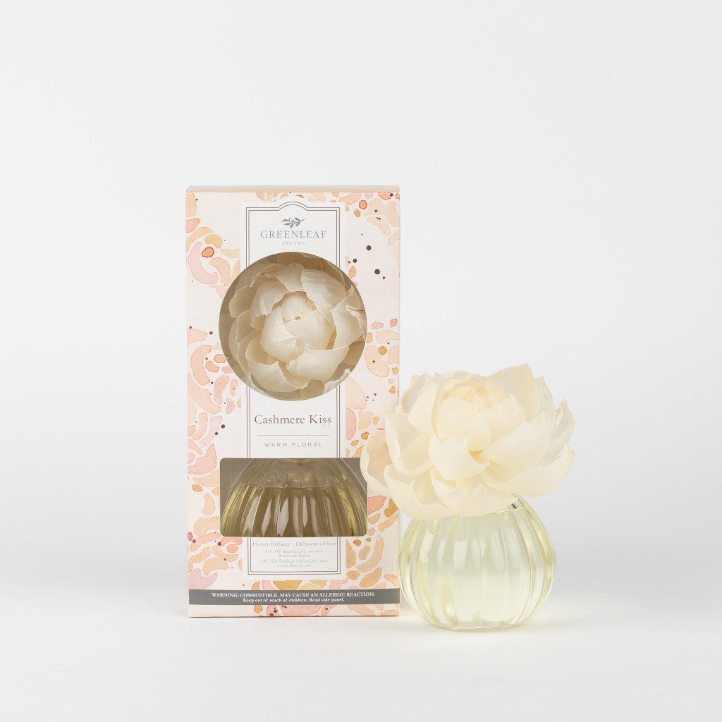 A Greenleaf Gifts Cashmere Kiss Flower Diffuser, featuring a cream flower-shaped top and yellow fragrance oil in a clear vase, is shown boxed and unboxed against a plain white background.