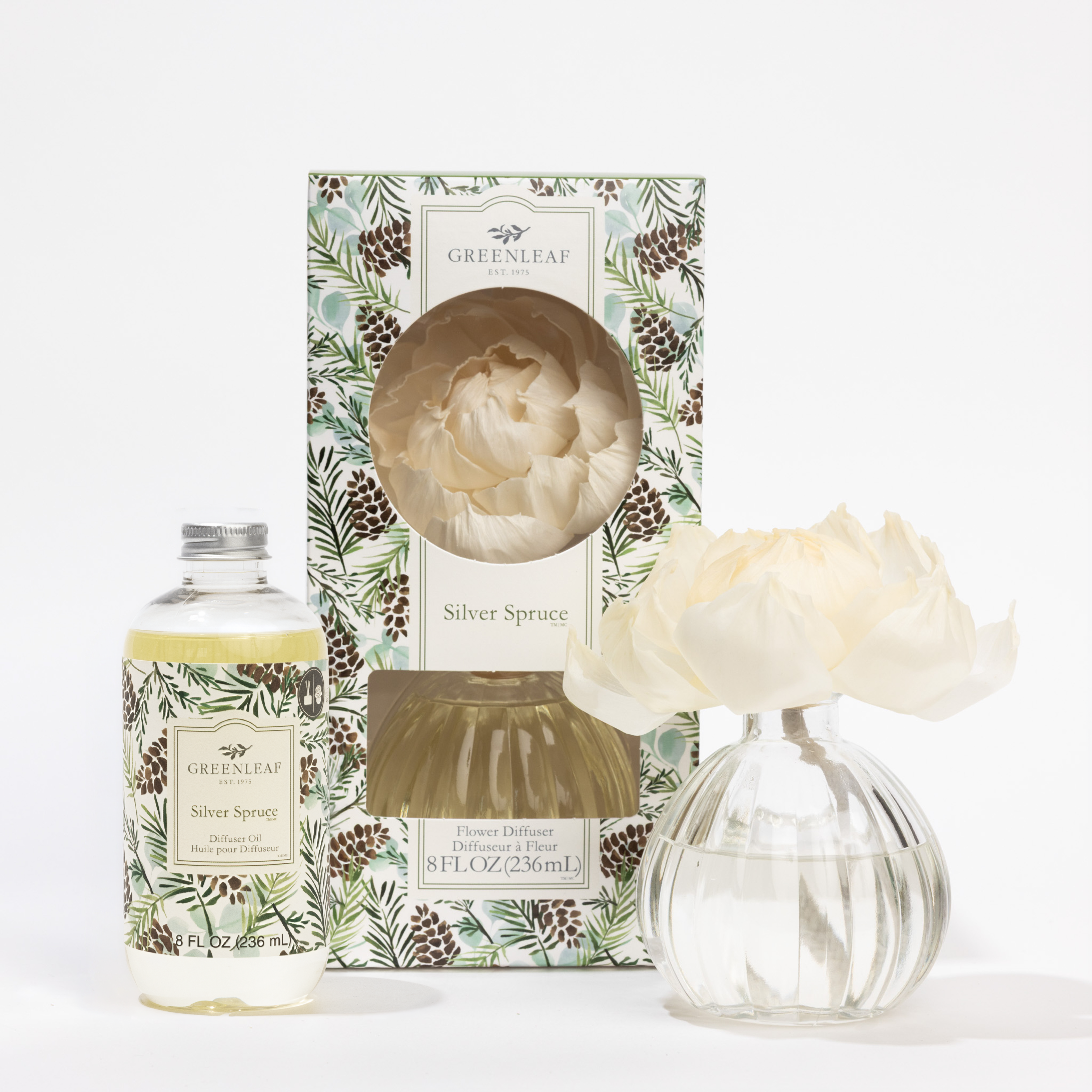 The Fast Bundle Silver Spruce Flower Diffuser & Fragrance Refill Oil set includes a festive pinecone-pattern box, a clear fragrance oil bottle, a glass vase with an artificial cream flower, and a refill for long-lasting scent.