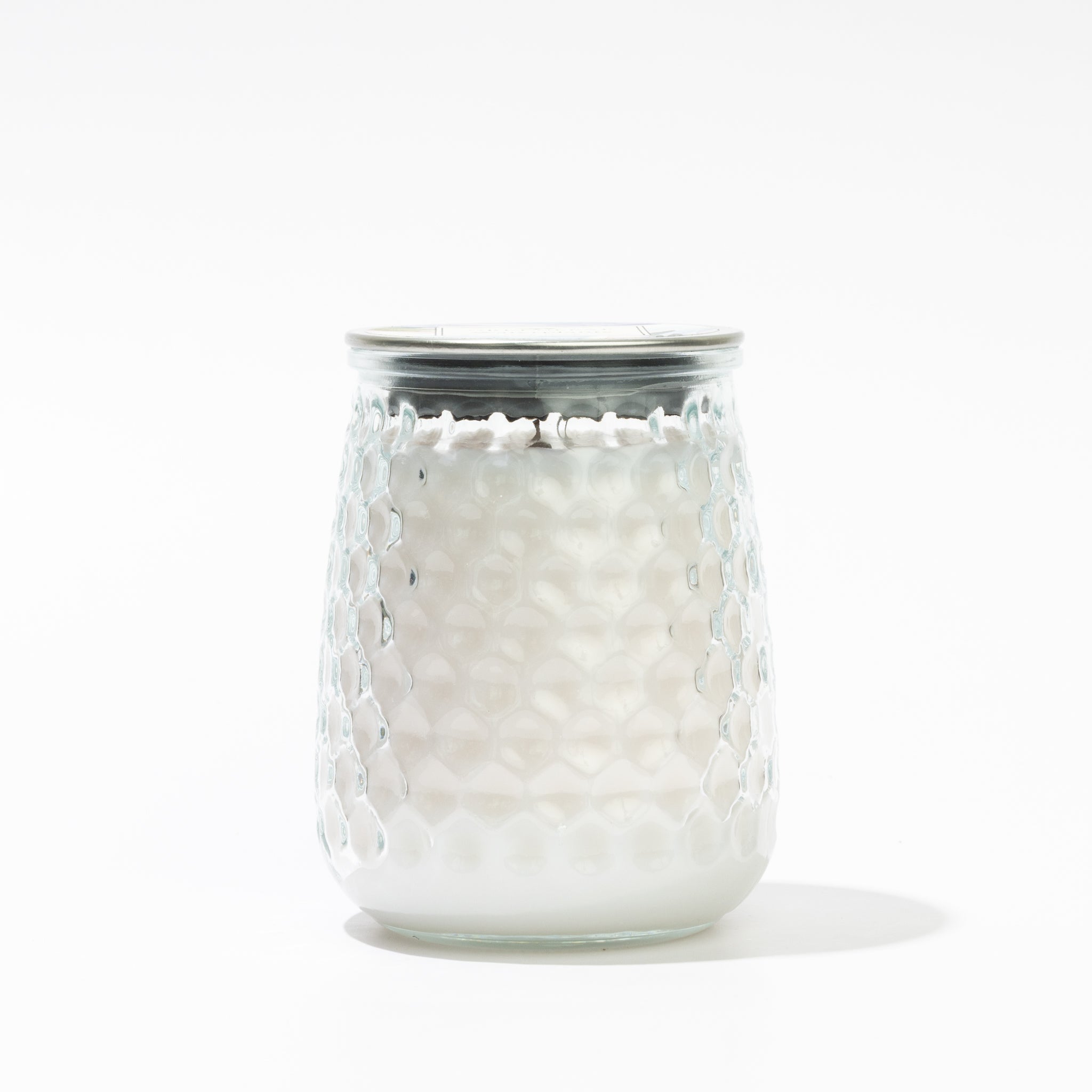 The Waterplants Signature Candle by Greenleaf Gifts is a white candle in a honeycomb-textured glass jar with a metallic lid, offering refreshing Waterplants notes against a simple white background.