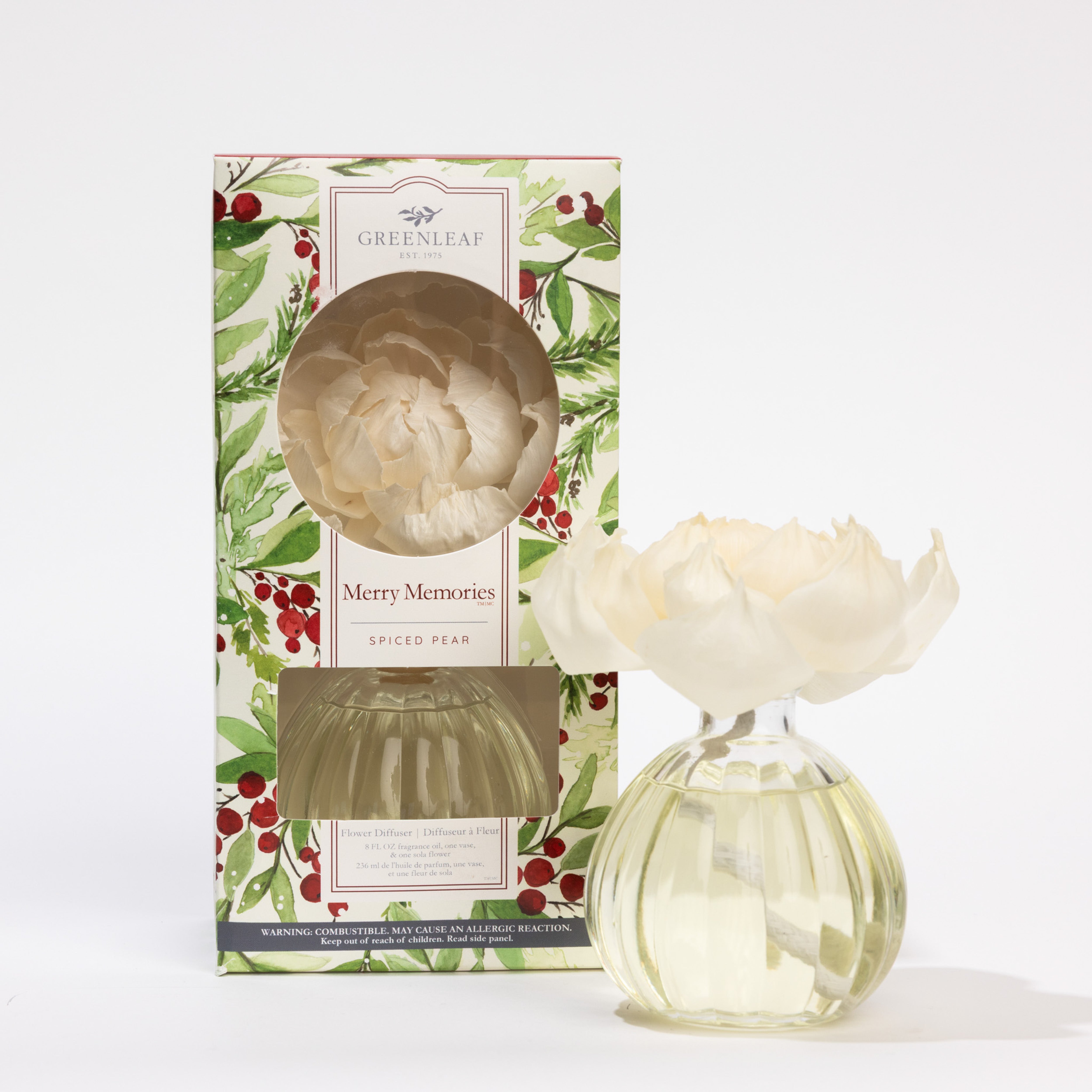 A Greenleaf Gifts Merry Memories Flower Diffuser with a sola paper flower top is shown beside its decorative box adorned with green leaves and red berries.