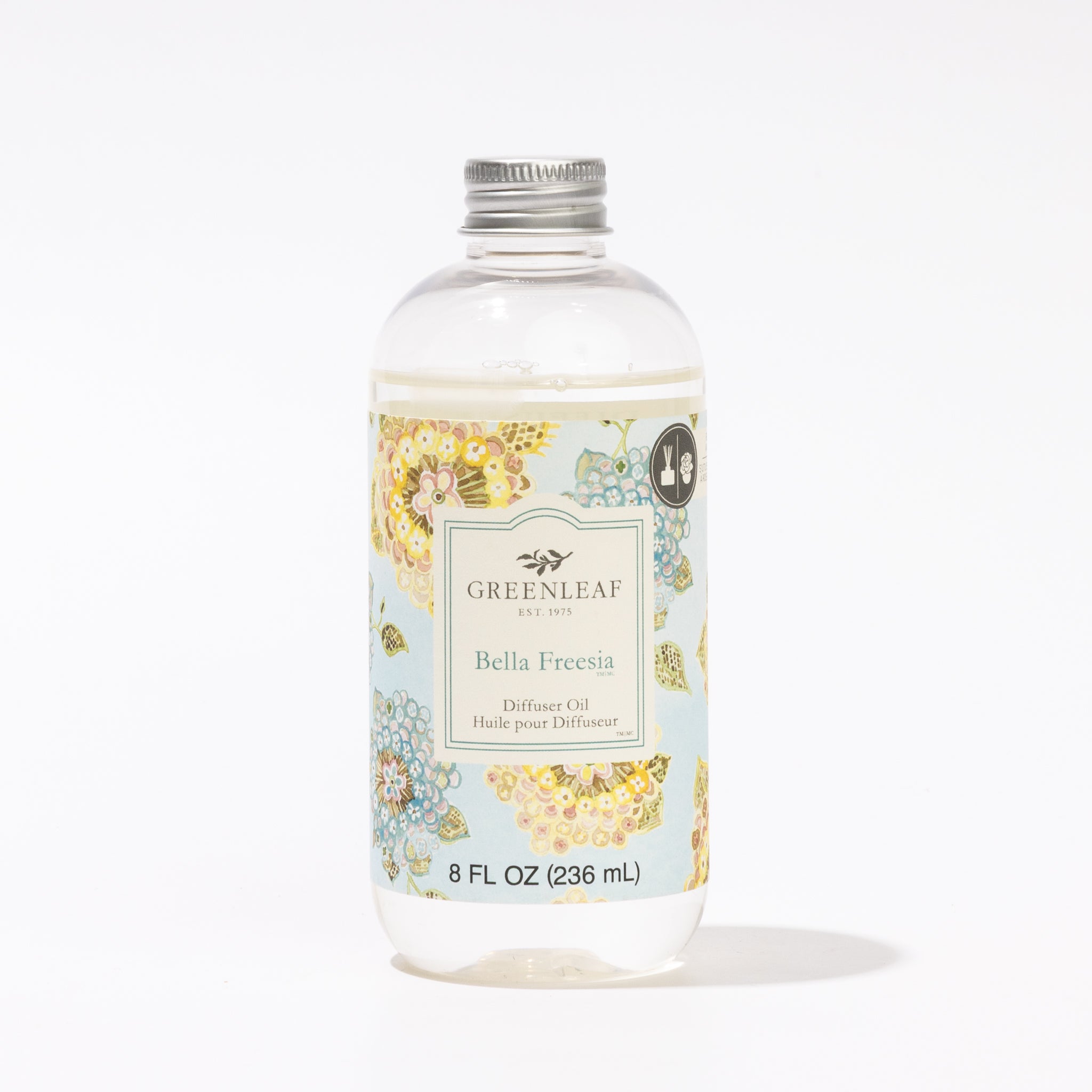 A clear plastic bottle of Greenleaf Gifts Bella Freesia Diffuser Oil (8 fl oz/236 ml) with a silver cap features pastel floral designs on a white label, capturing the fresh, delicate fragrance of Bella Freesia.