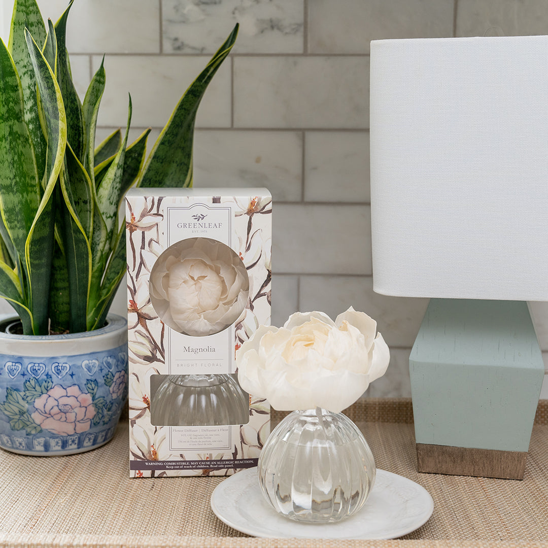 The Greenleaf Gifts Flower Diffuser-Magnolia (8 oz) features a white flower-shaped design in a glass vase and comes with a matching box. Enjoy up to 60 days of magnolia fragrance, perfect for adding elegance to your space.