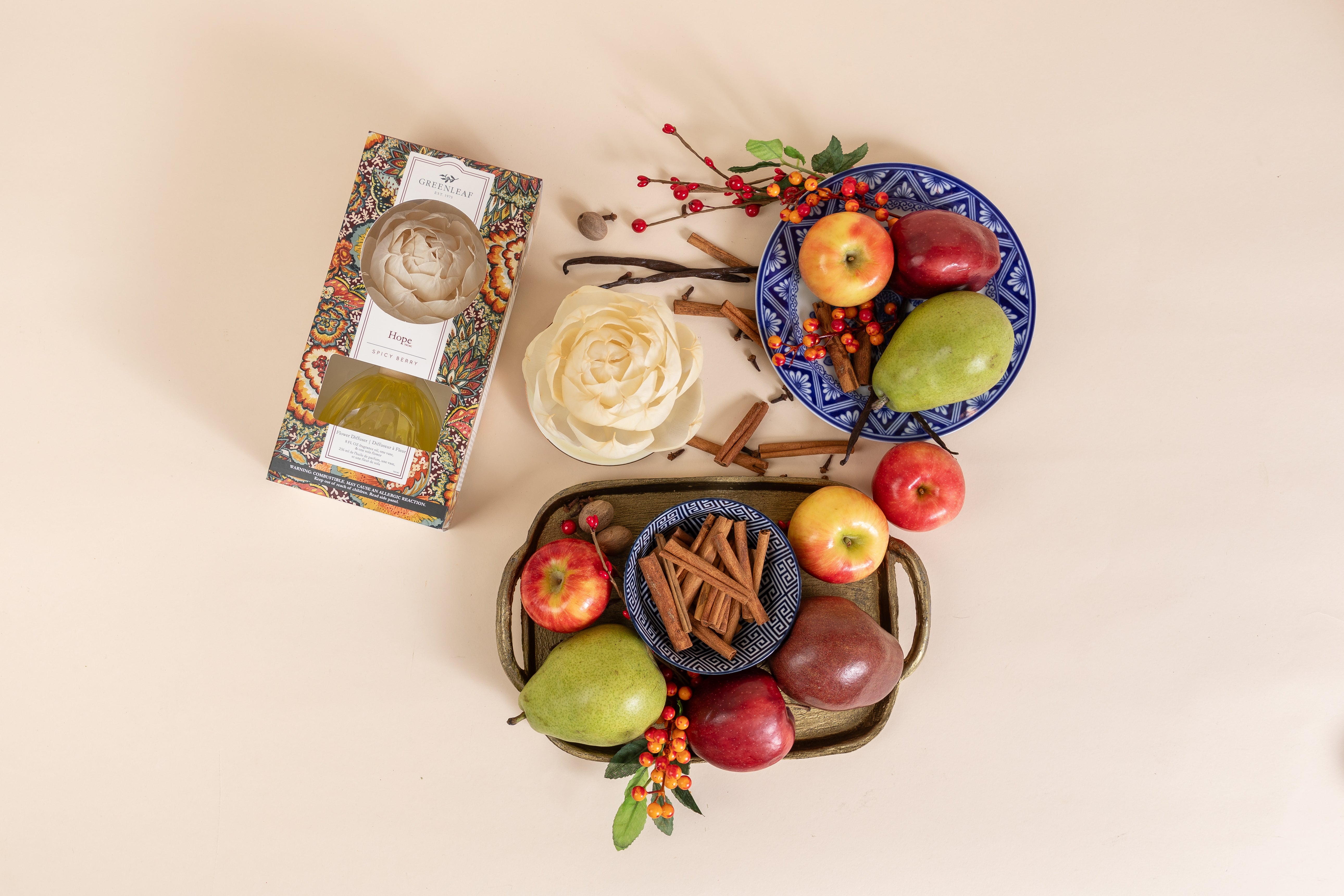 A flat lay of fresh apples, pears, and cinnamon sticks on colorful plates, featuring a decorative floral box and the Greenleaf Gifts Hope Flower Diffuser—all set against a light beige background.