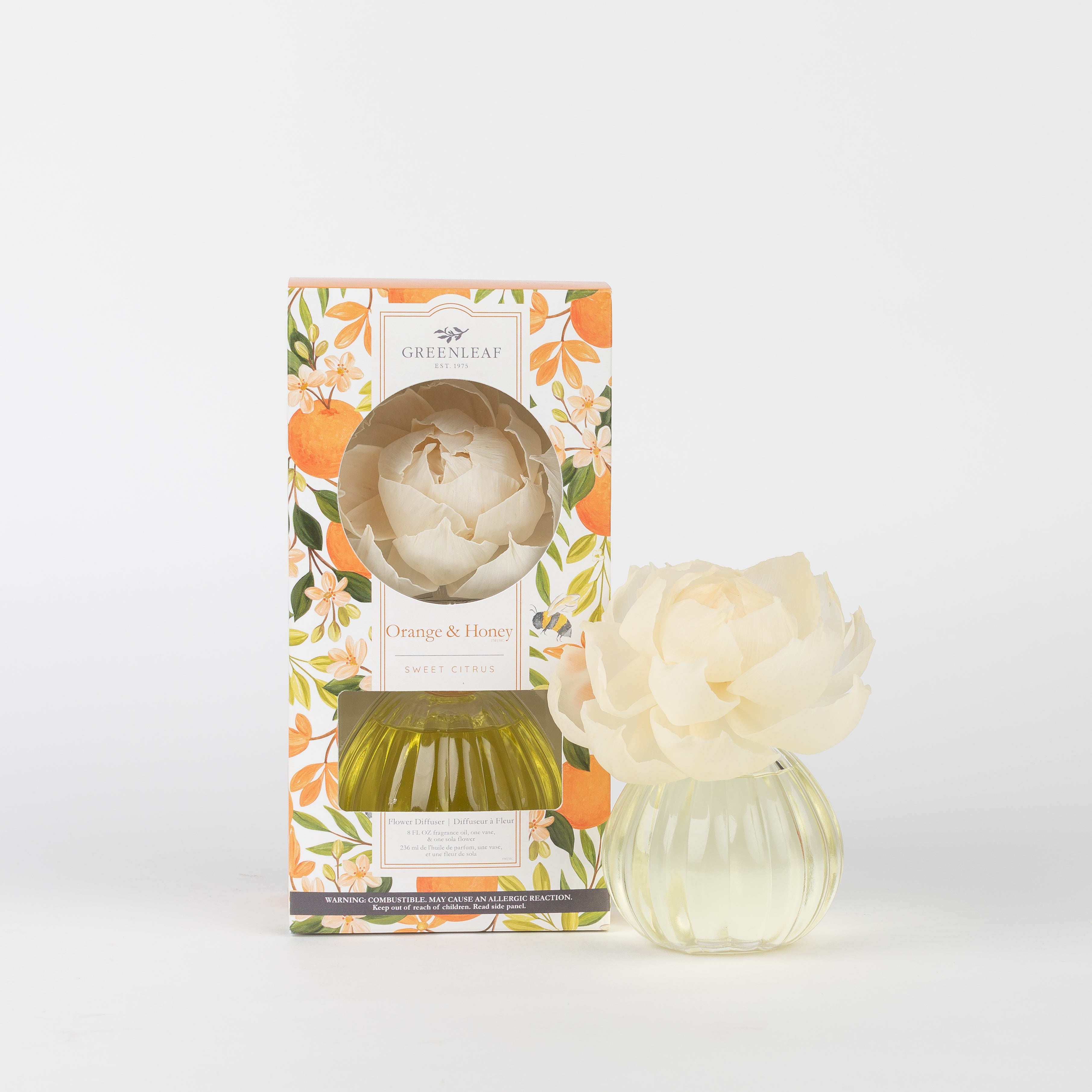 A Greenleaf Gifts Orange & Honey Flower Diffuser with a sola paper flower sits next to its floral-patterned box with orange and yellow accents, both filled with lasting fragrance.