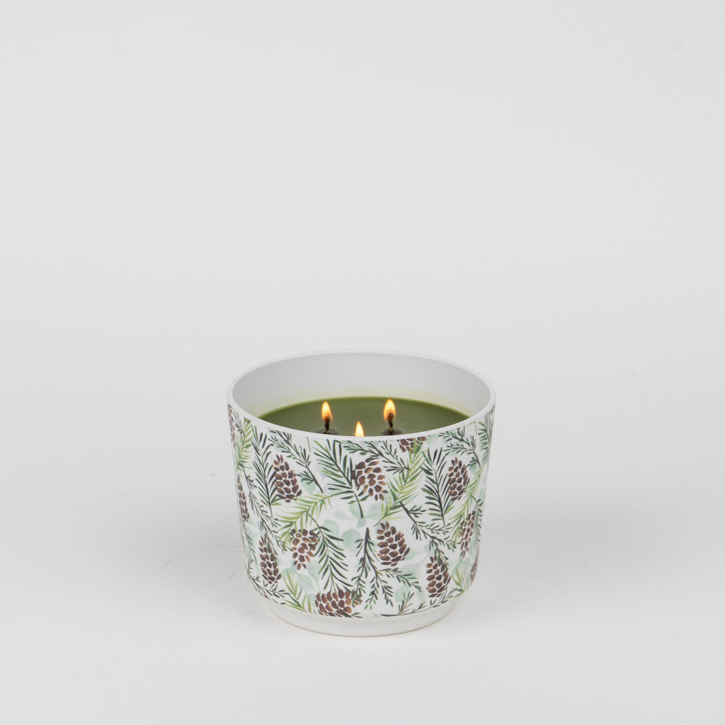 The Greenleaf Gifts Silver Spruce Patterned 3 Wick Candle features a green hue and silver spruce scent in a white ceramic container with pinecone and pine needle designs, shown on a plain white background.