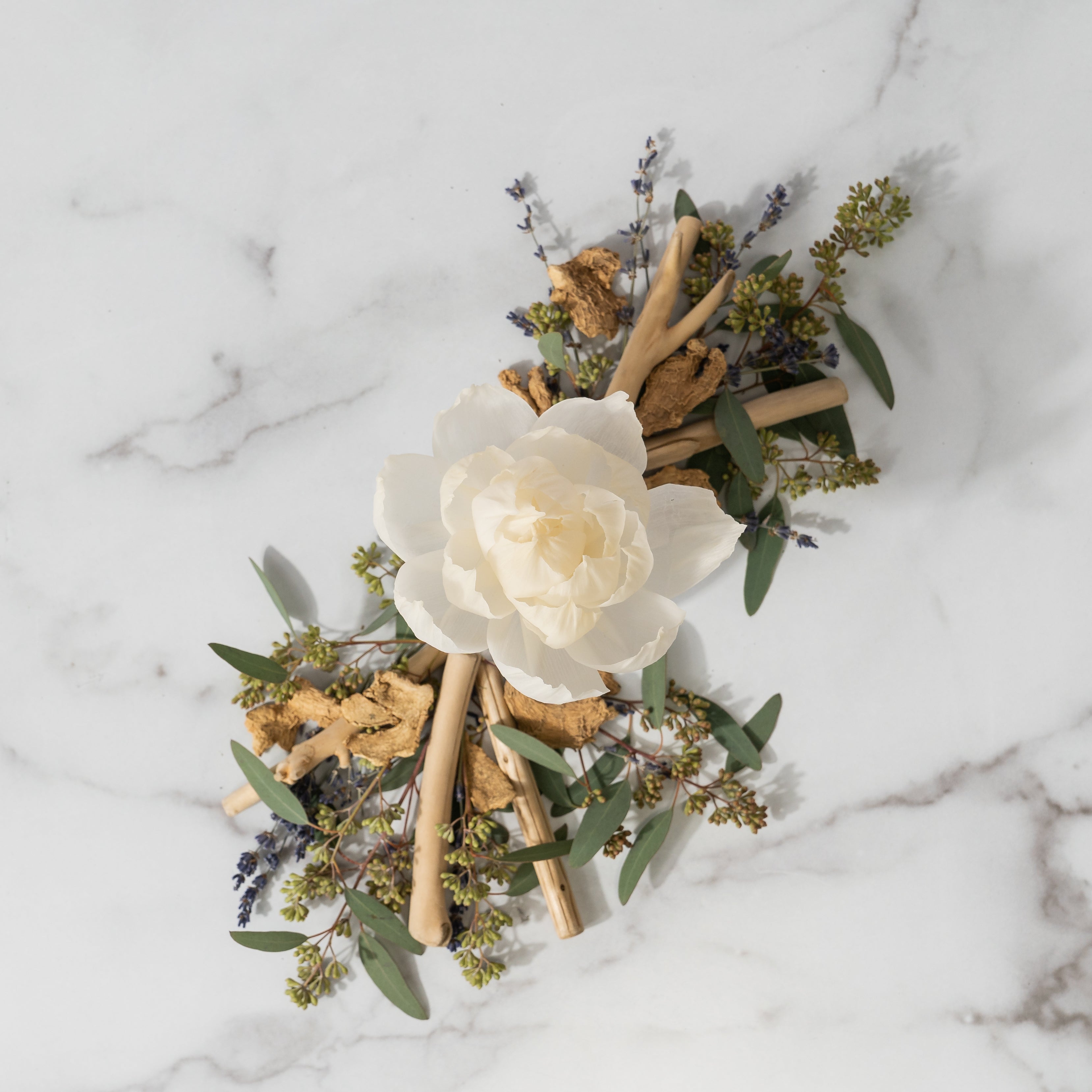 The Haven Flower Diffuser by Greenleaf Gifts features a white flower with wooden sticks, dried lavender, greenery, and cork pieces on a white marble base. Product size: 4.5x3.5x9.0 inches.