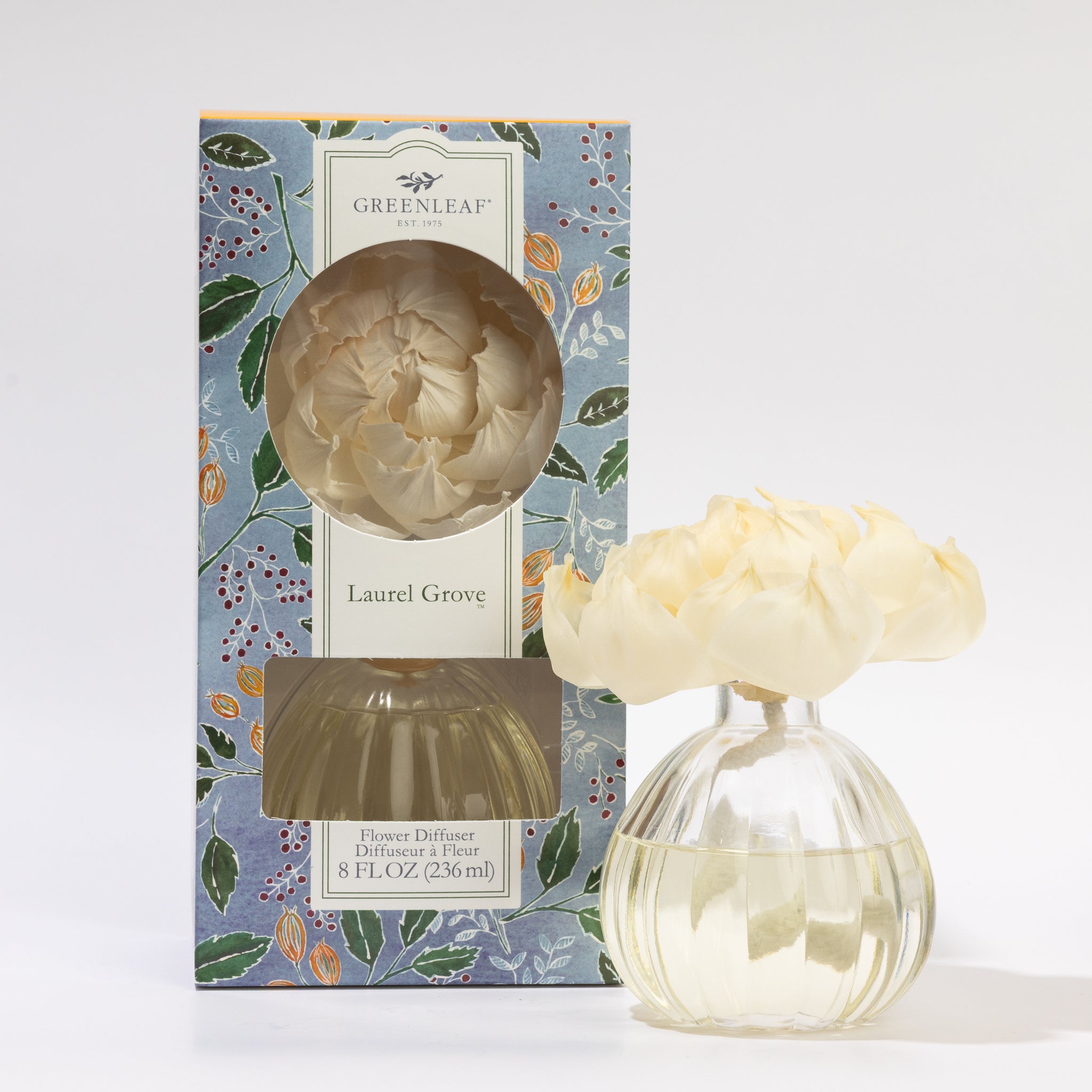 The Greenleaf Gifts Laurel Grove Flower Diffuser features a floral-patterned box, a round glass bottle filled with fragrance oil, and is topped with cream-colored sola paper flowers.