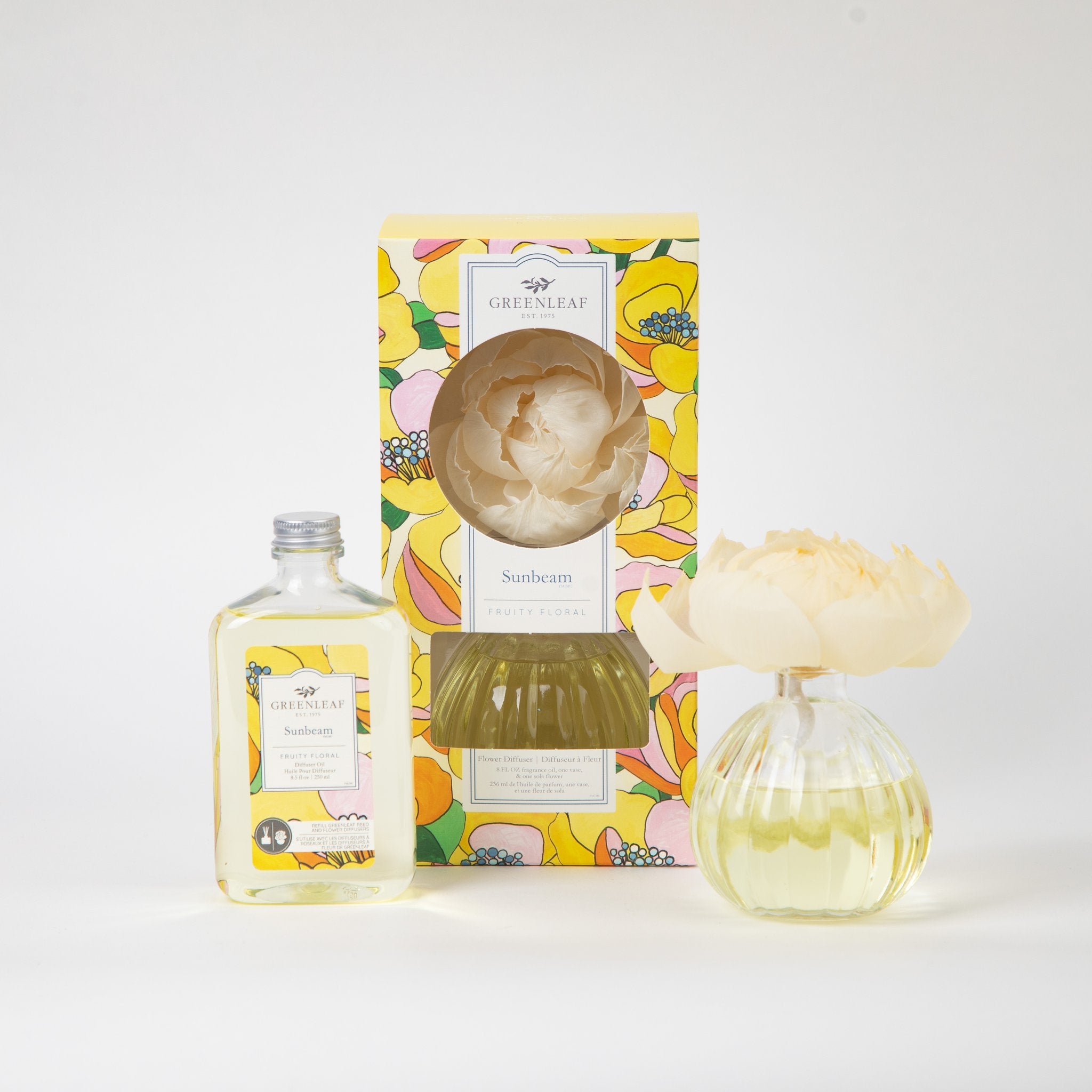 The Fast Bundle Sunbeam Flower Diffuser & Fragrance Oil Refill includes a clear bottle of fragrance oil, a decorative flower in a round glass vase, and comes in a vibrant yellow and orange floral box.