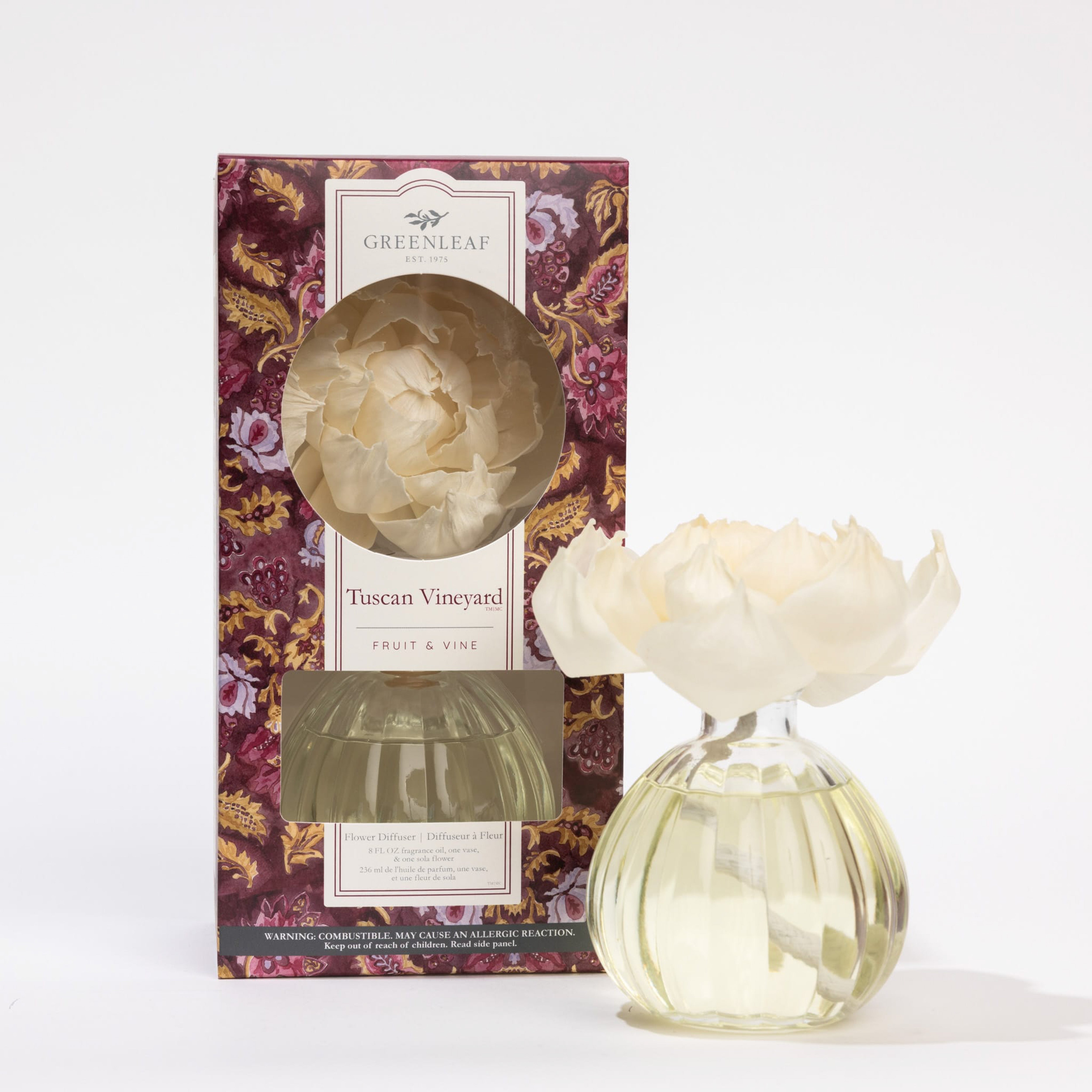 A Greenleaf Gifts Tuscan Vineyard Flower Diffuser (8 oz, GLG966521S) with a cream flower top sits beside its burgundy and gold floral box, offering up to 60 days of continuous fragrance.
