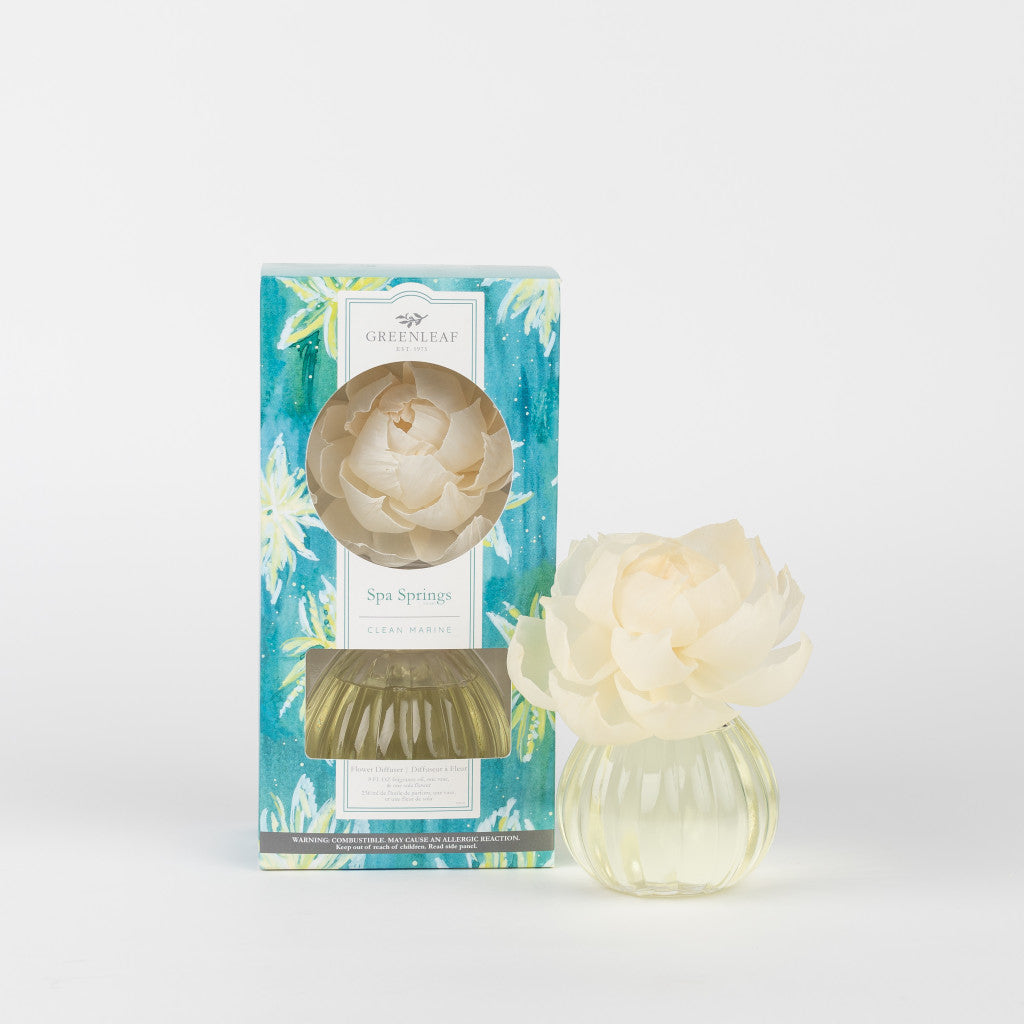 The Spa Springs Flower Diffuser by Greenleaf Gifts features a white floral accent on a ribbed glass vase and comes in colorful blue-green packaging. Use with Reed Diffuser Oil Refills for long-lasting fragrance.